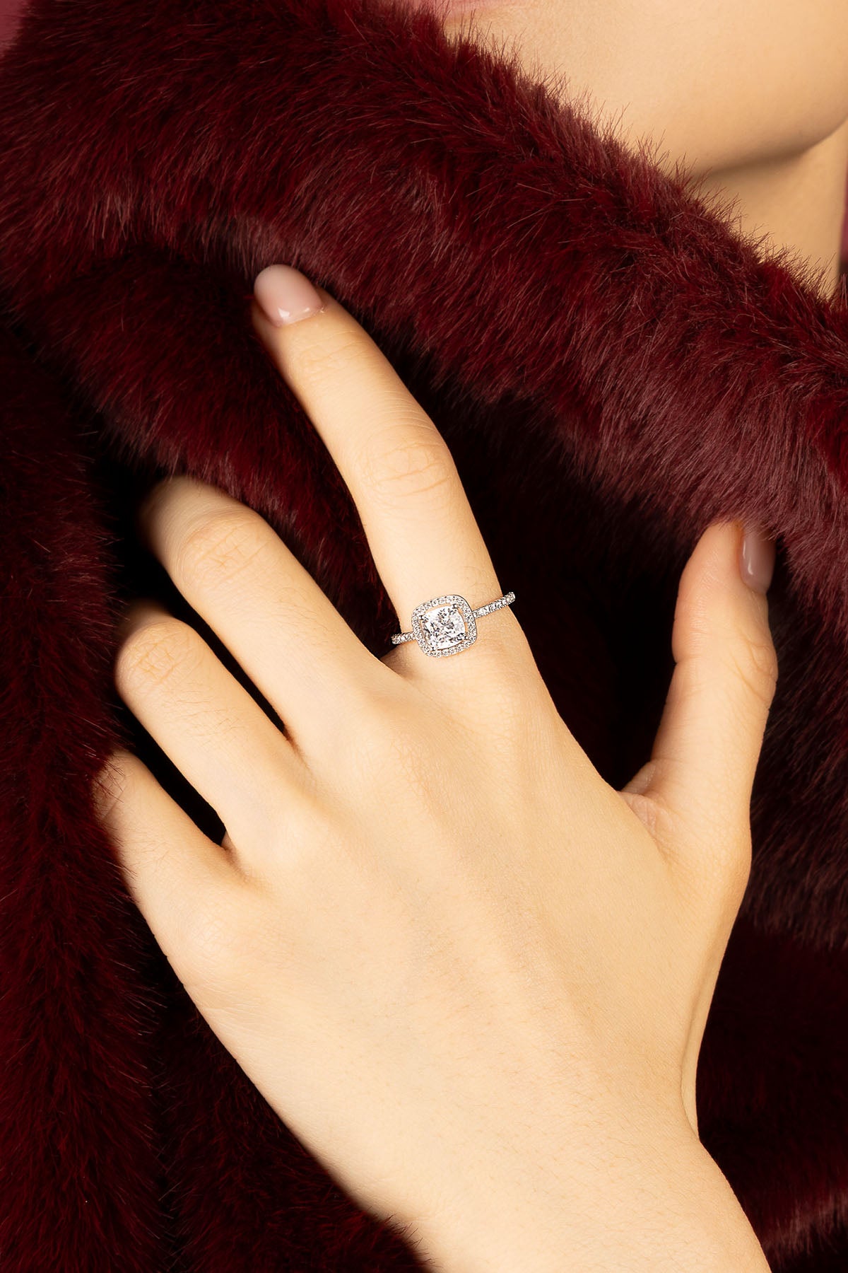 Woman wearing APM ring, a luminous whisper against velvet burgundy.