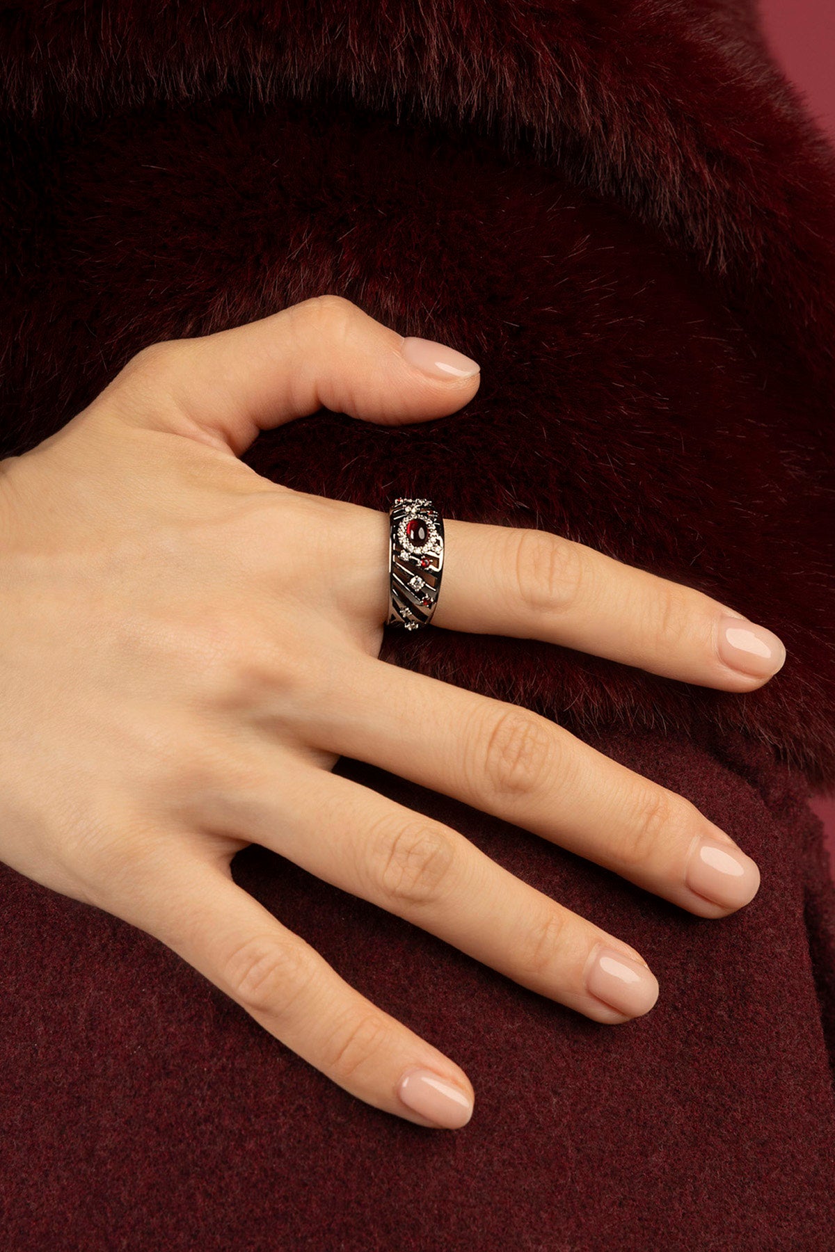 Woman wearing APM Morse Ring, a quiet spark against burgundy softness.