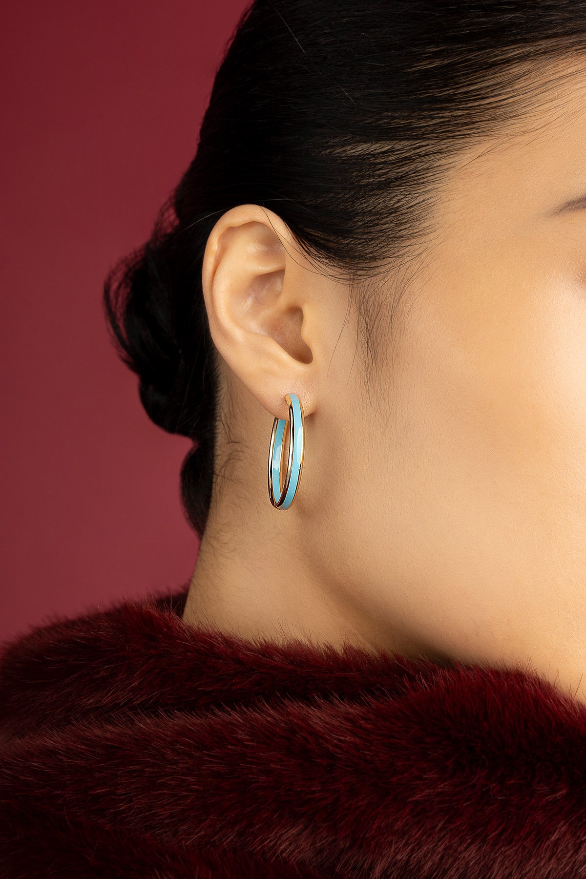 Woman wearing APM Hoop Earrings, a bold turquoise stroke on golden curves.