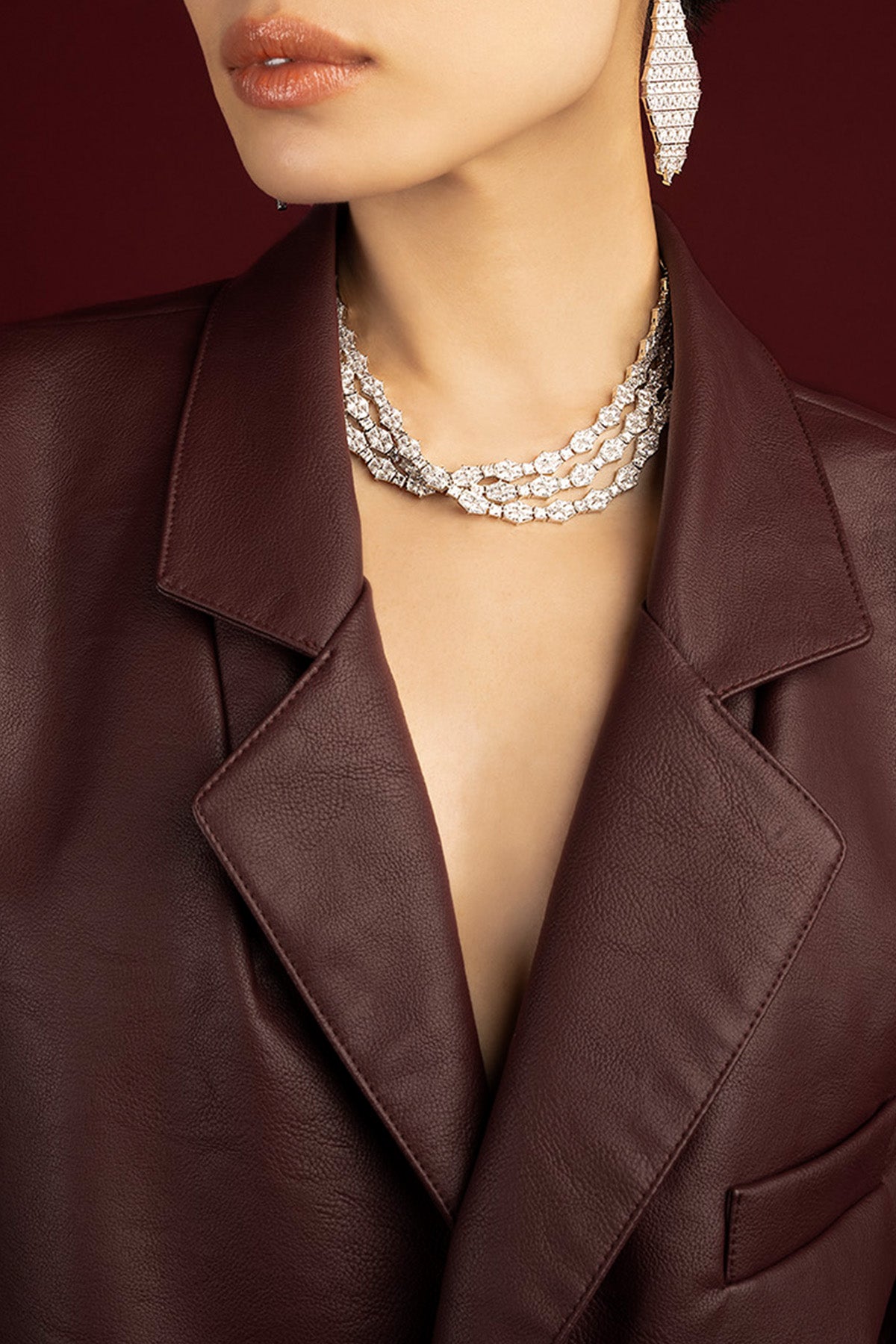 Woman wearing APM Monaco layered choker necklace, radiant elegance against rich leather.