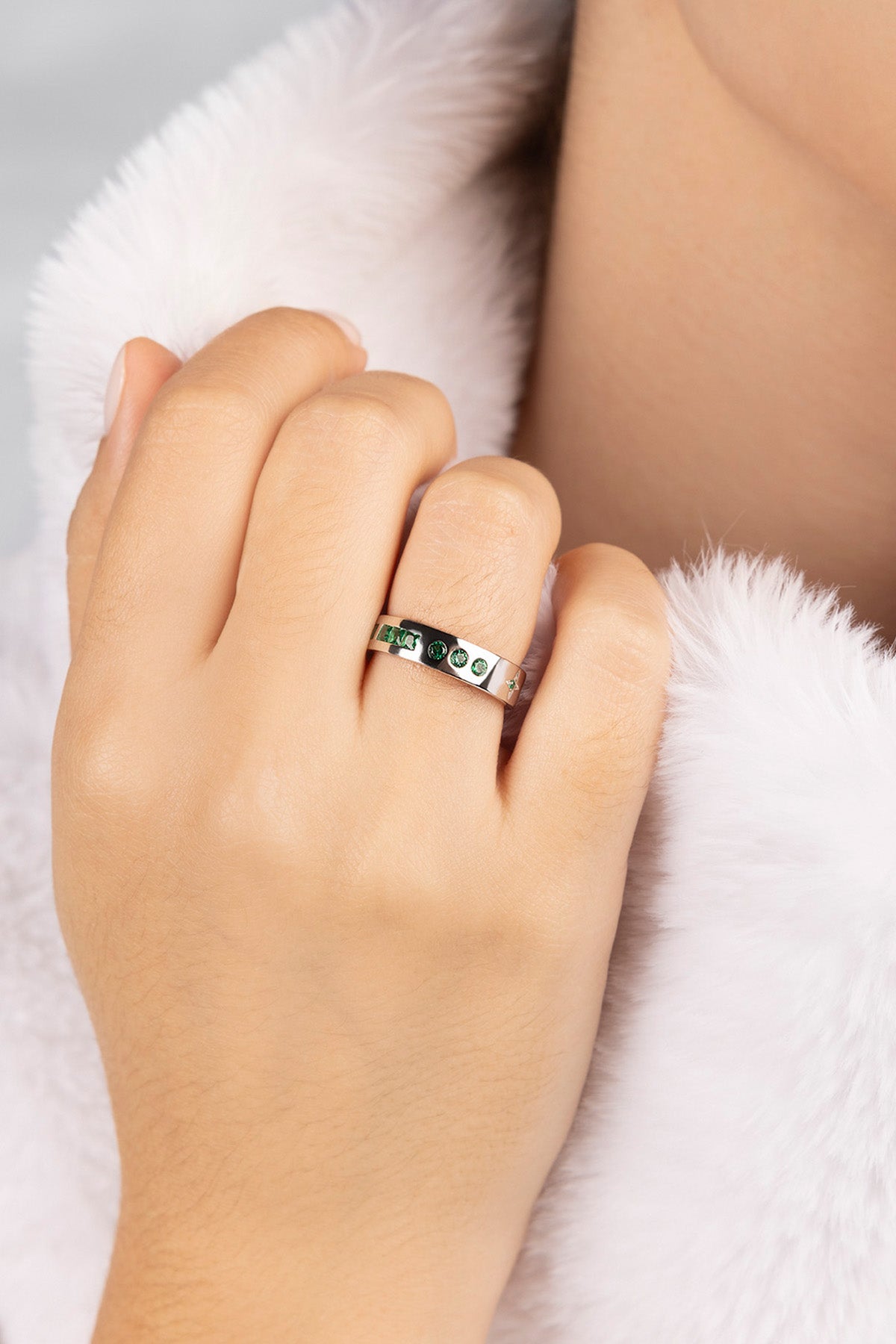 Hand wearing a ring on a white fur background