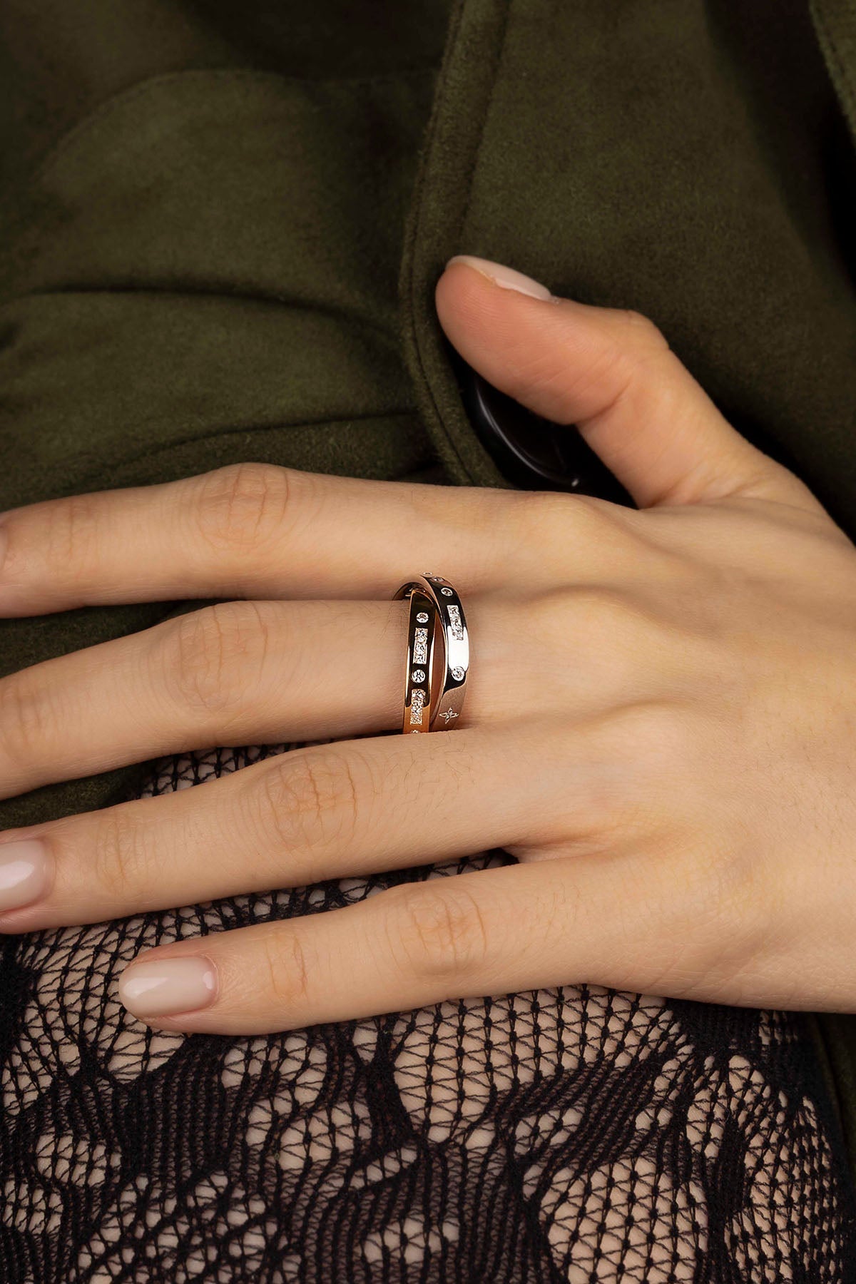 Close-up of a hand wearing two rings with a dark background