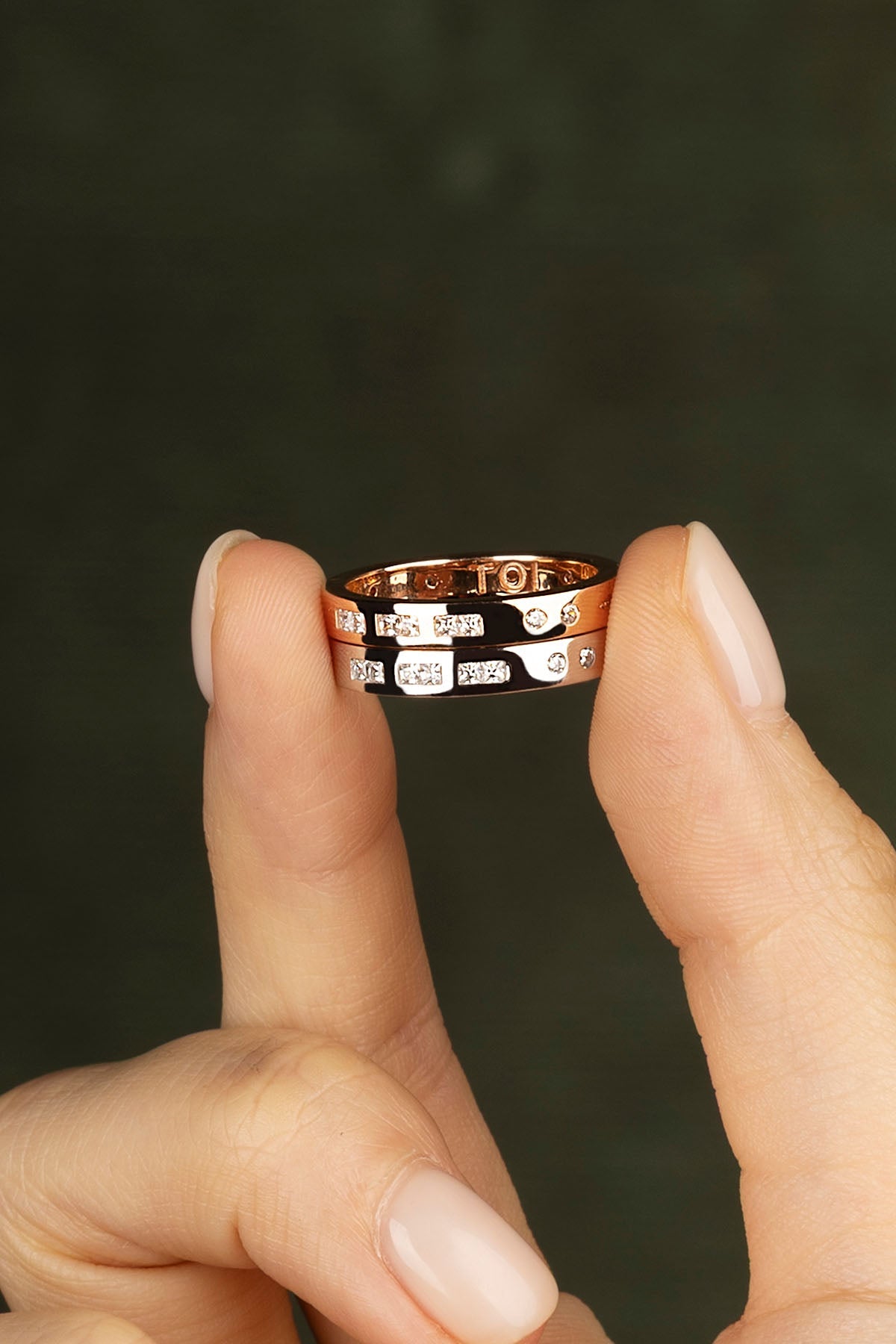 Two rings being worn on a finger against a dark background
