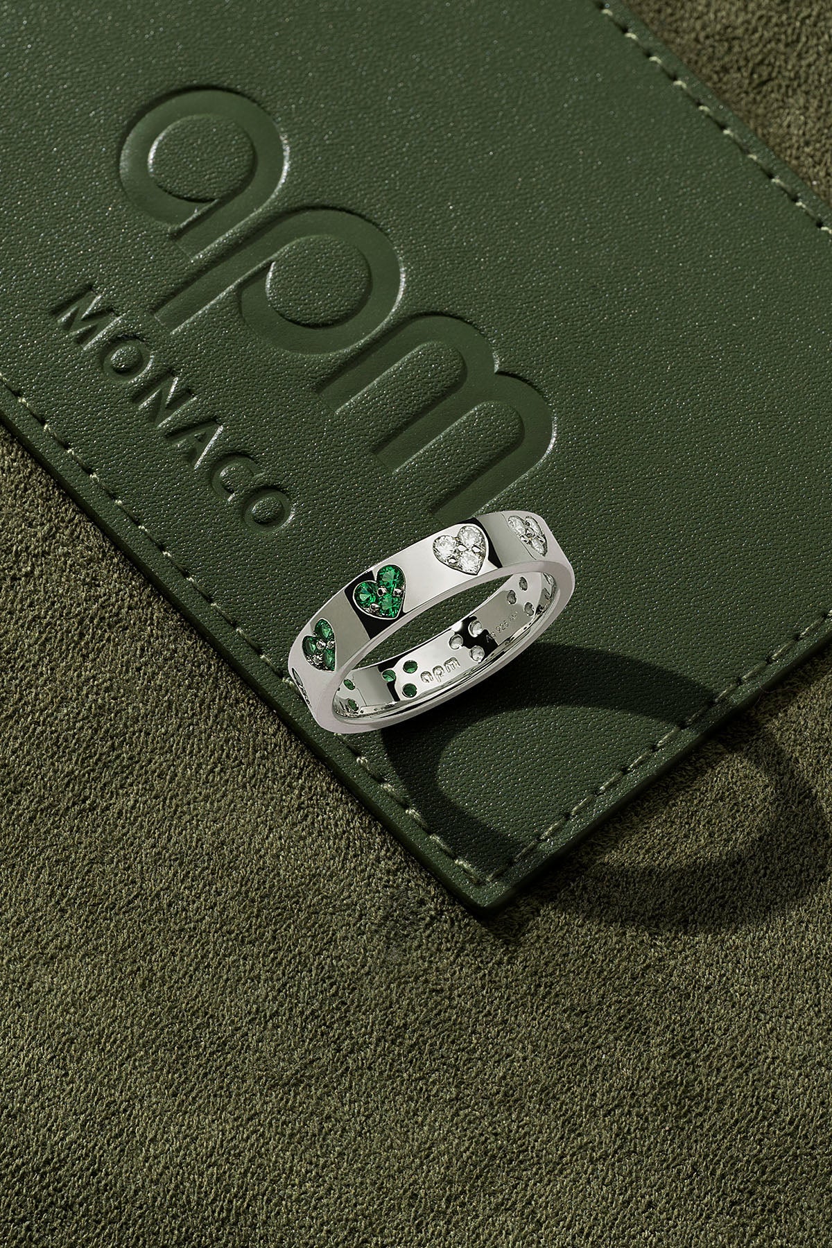 Silver ring with green stones on a green leather surface