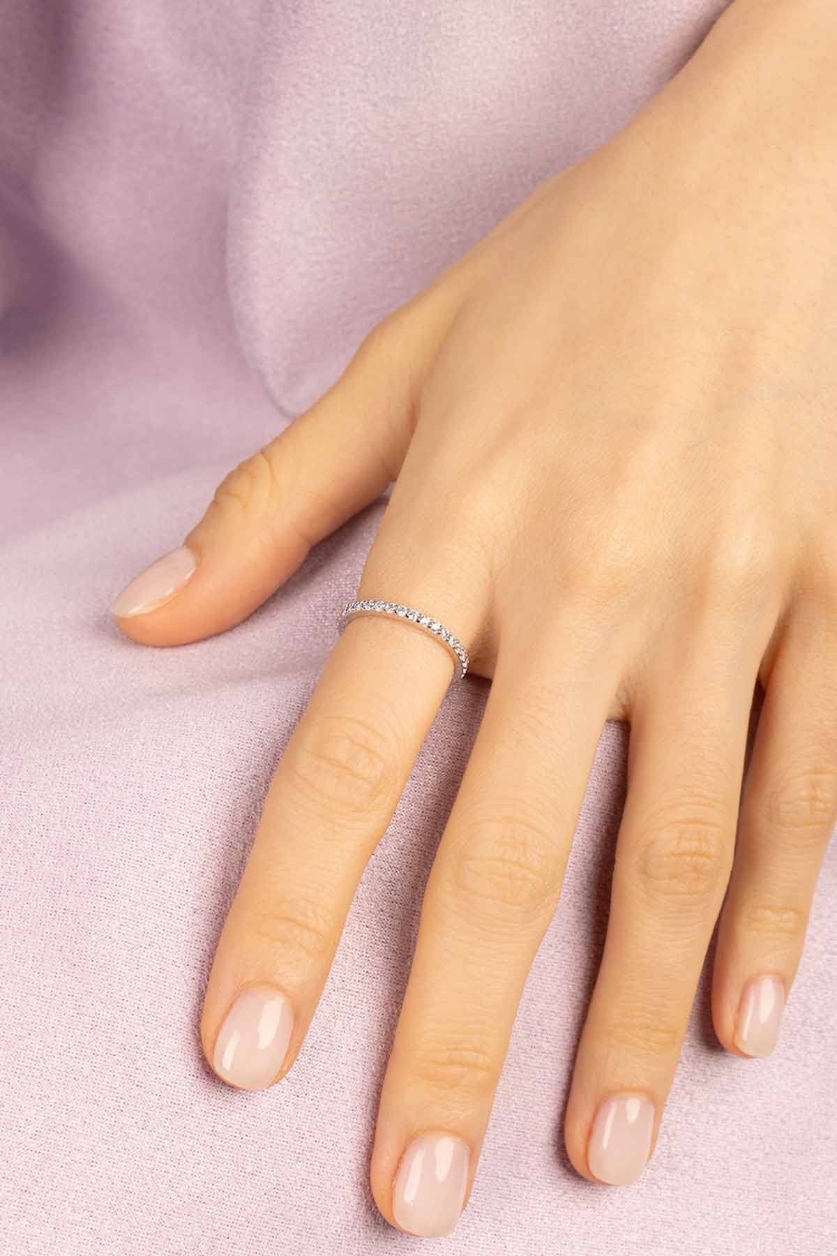 Hand wearing APM MONACO linear pave silver ring on a light purple fabric background