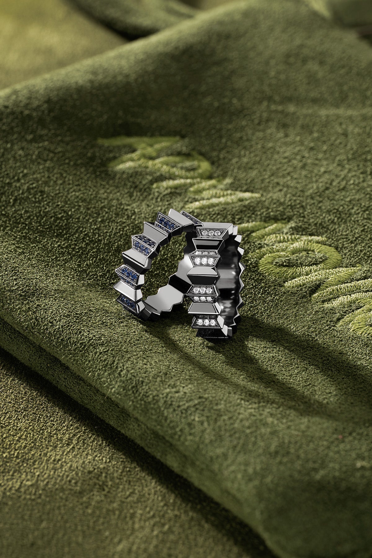 Silver ring with embedded stones on a green fabric background