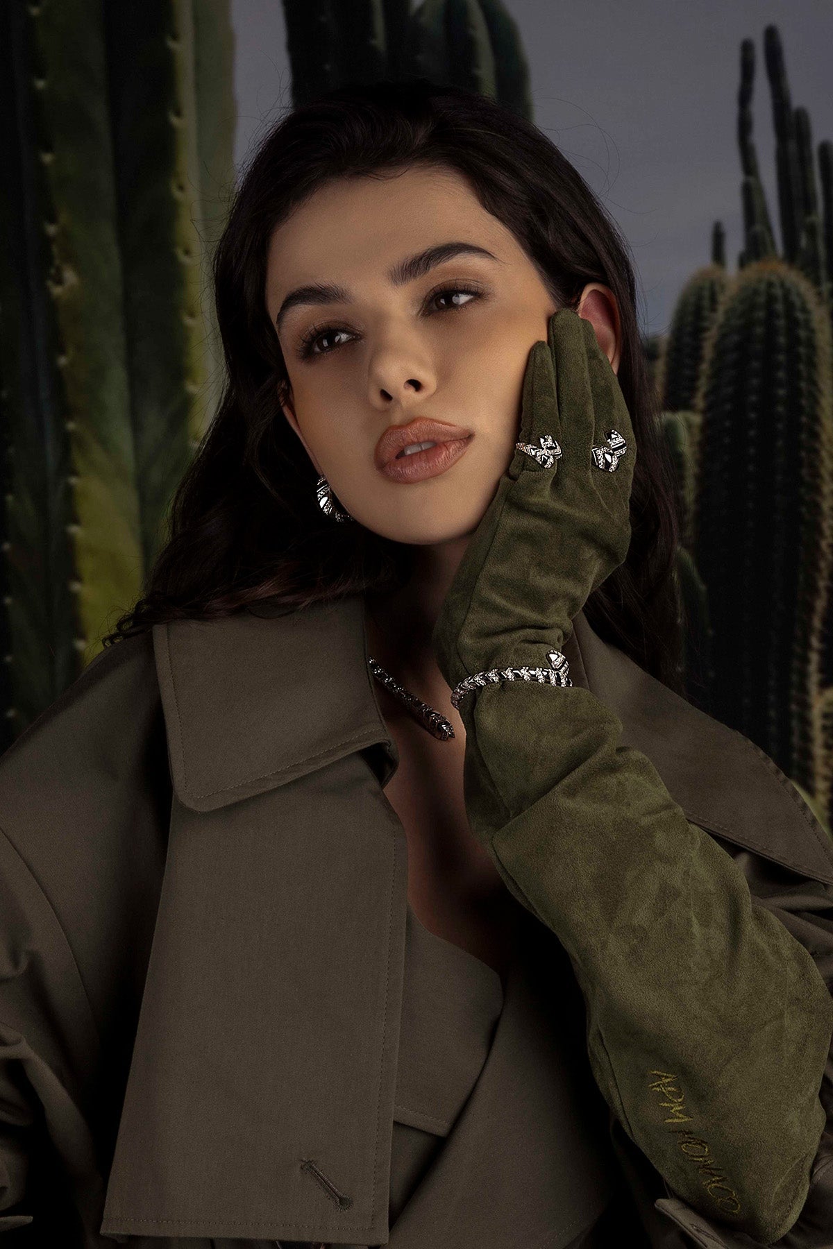 Woman wearing APM Monaco Kaa Ring in silver with green glove in front of a cactus background