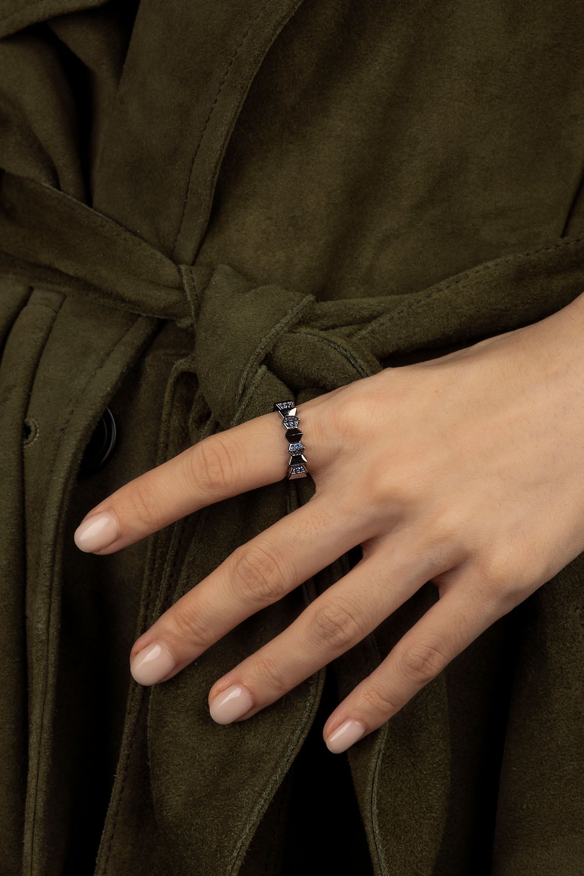 Close-up of a hand wearing a ring with a dark coat in the background
