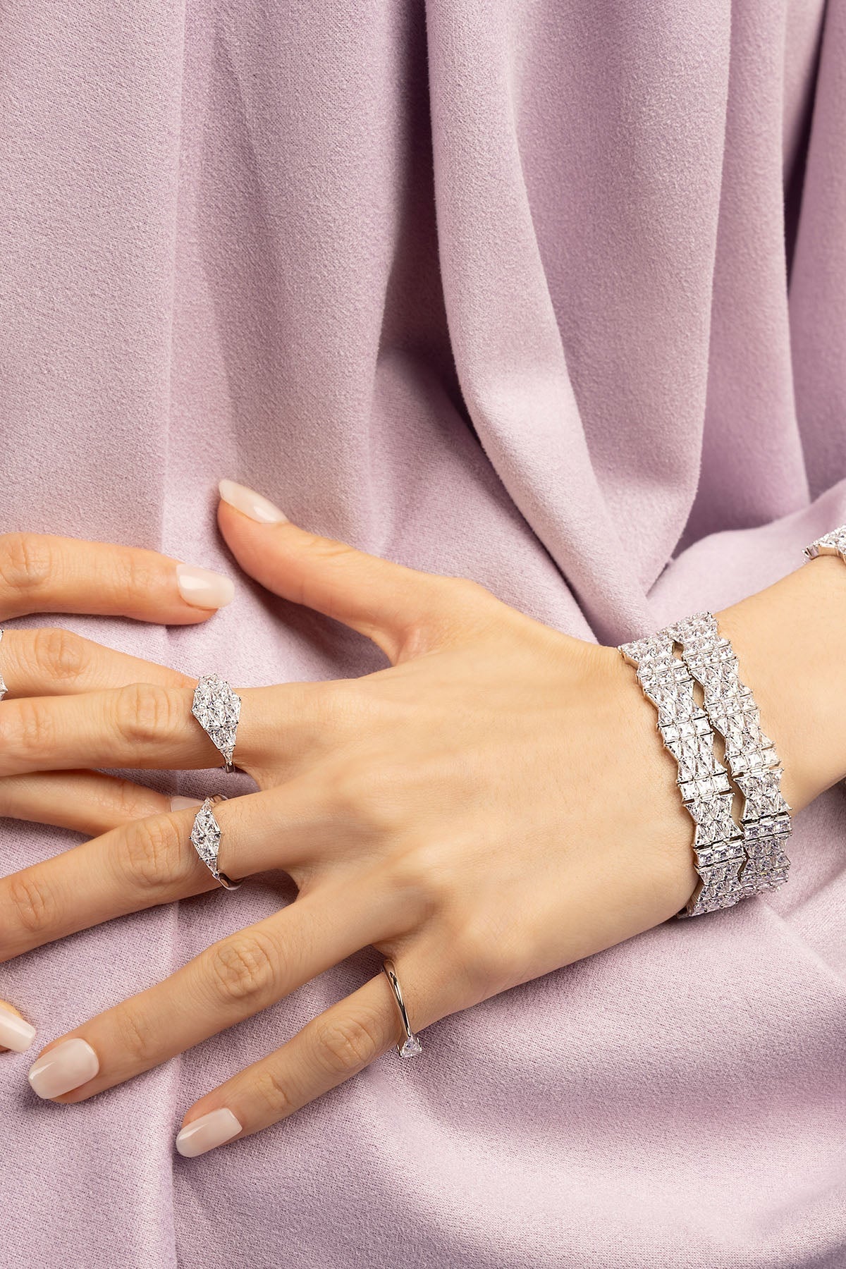 Hand wearing a zirconia ring on a soft purple fabric background