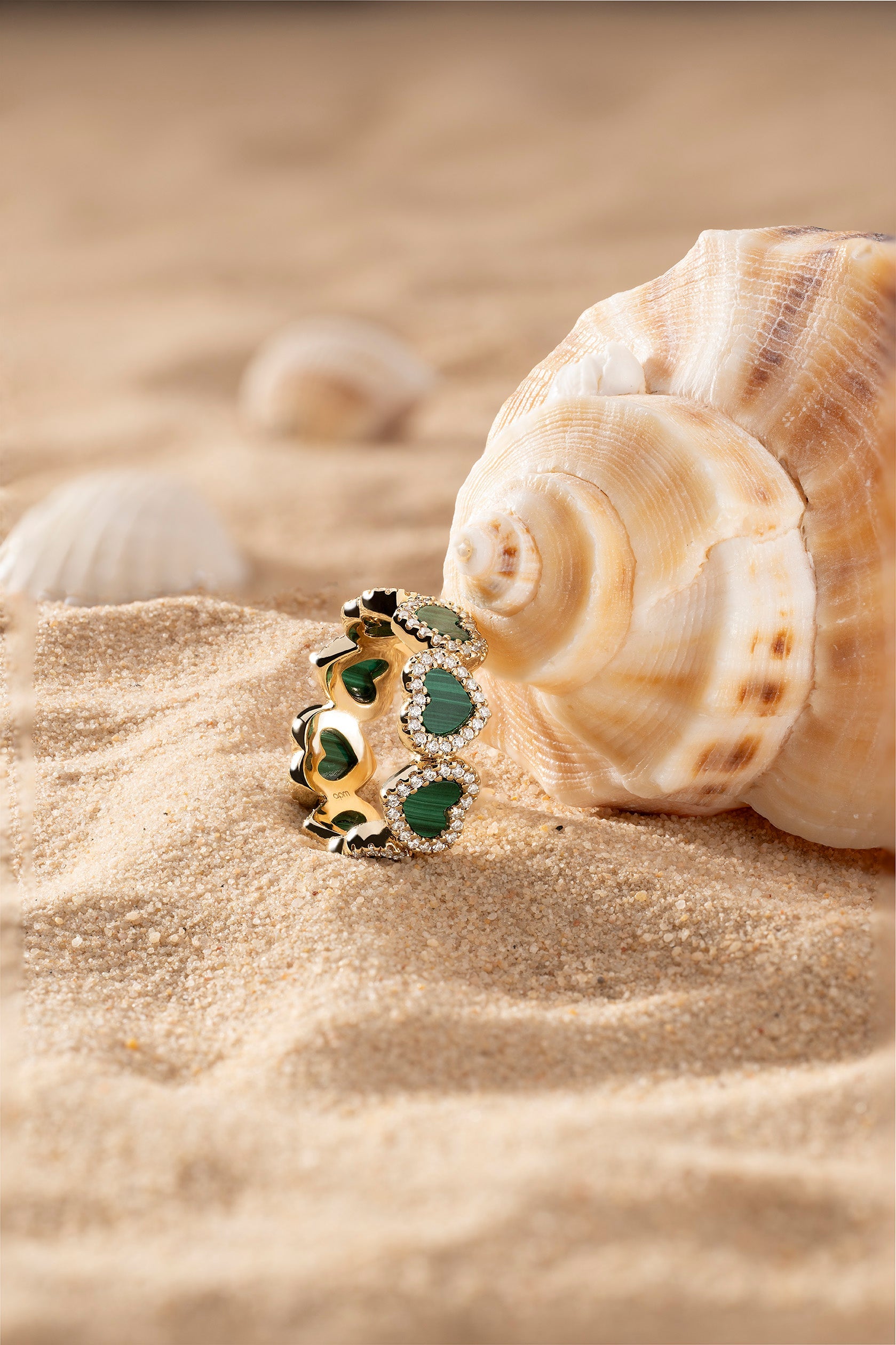 Rings APM Monaco: gold ring featuring green heart-shaped accents and small stones between them.