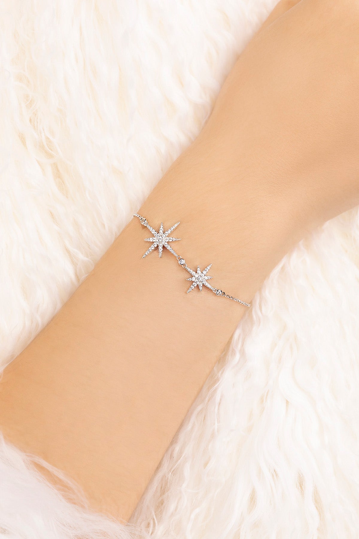 Silver bracelet with star designs on a wrist against a soft white background