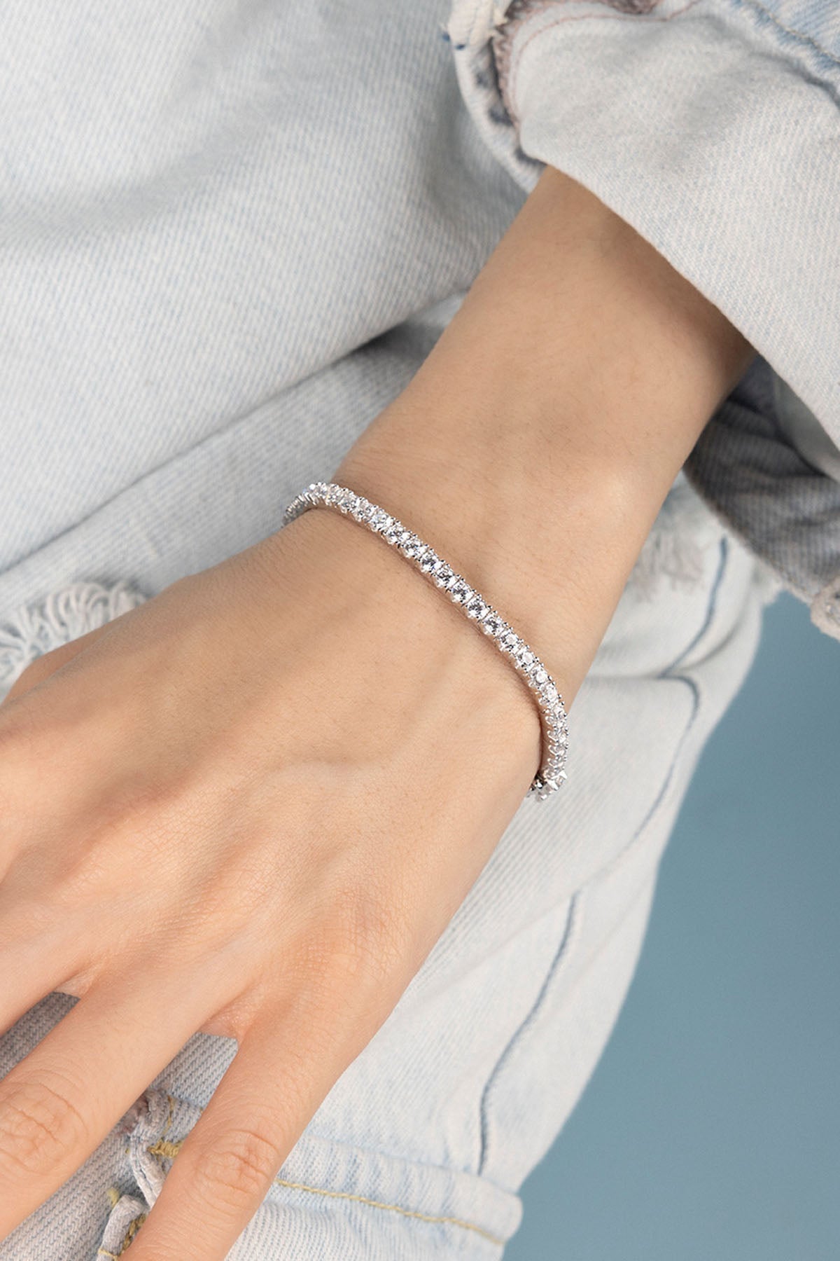 Bracelets APM Monaco, white pavé gemstone tennis bracelet on a woman's wrist.