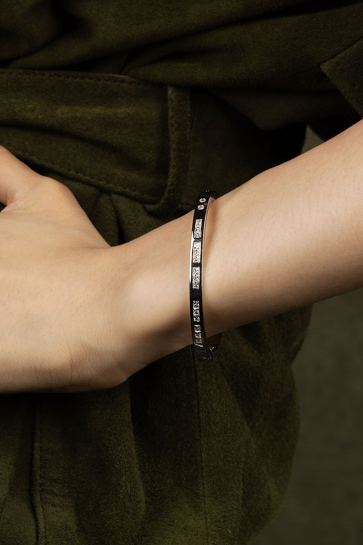 Person wearing a black bracelet against a dark background.