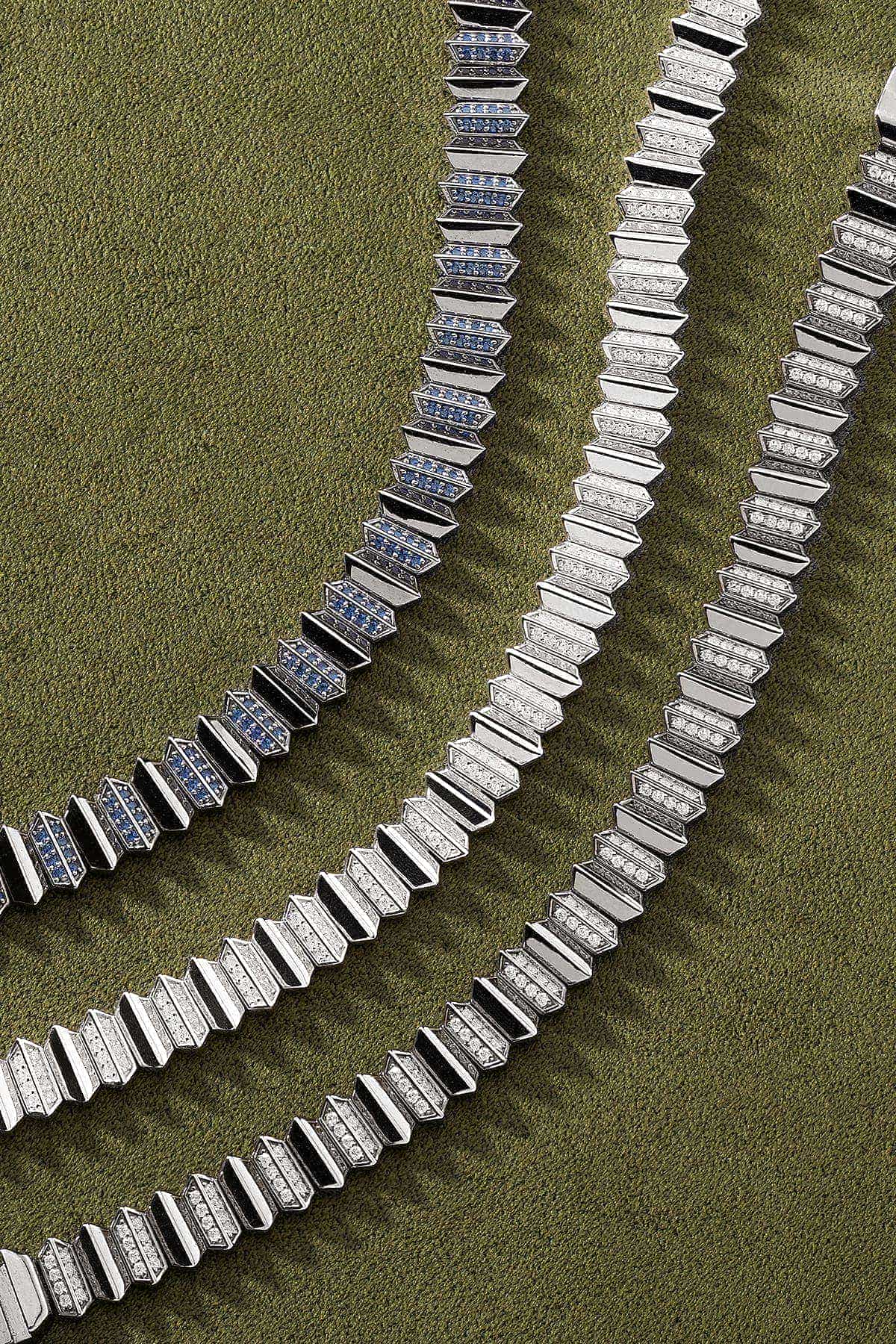 Silver necklaces on a textured green surface