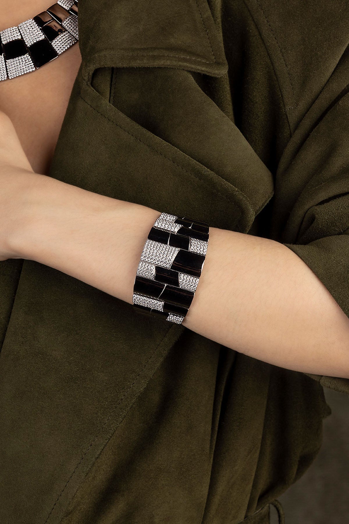 Person wearing a bracelet on an arm with a green jacket.