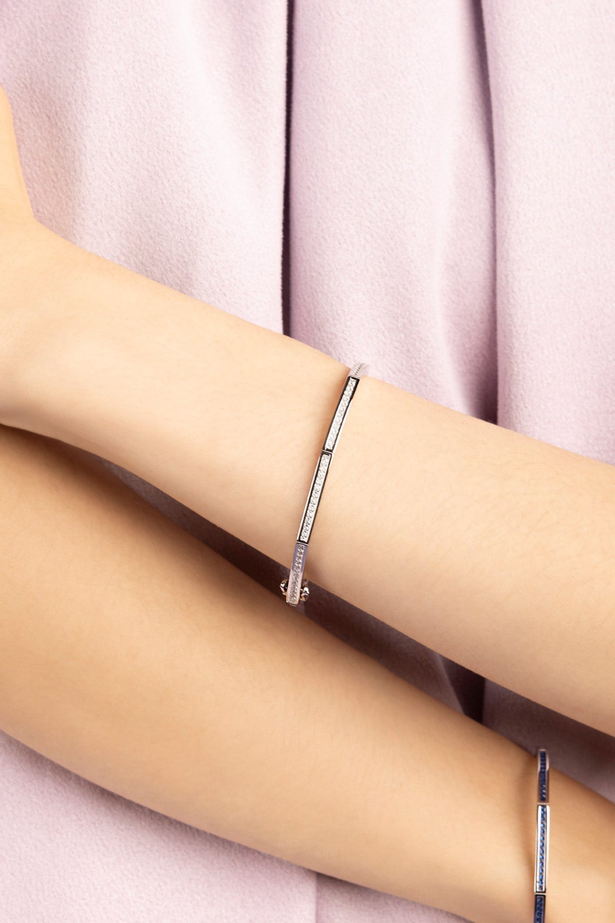 Silver bangle paved with white zirconia stones worn by model wearing purple shirt