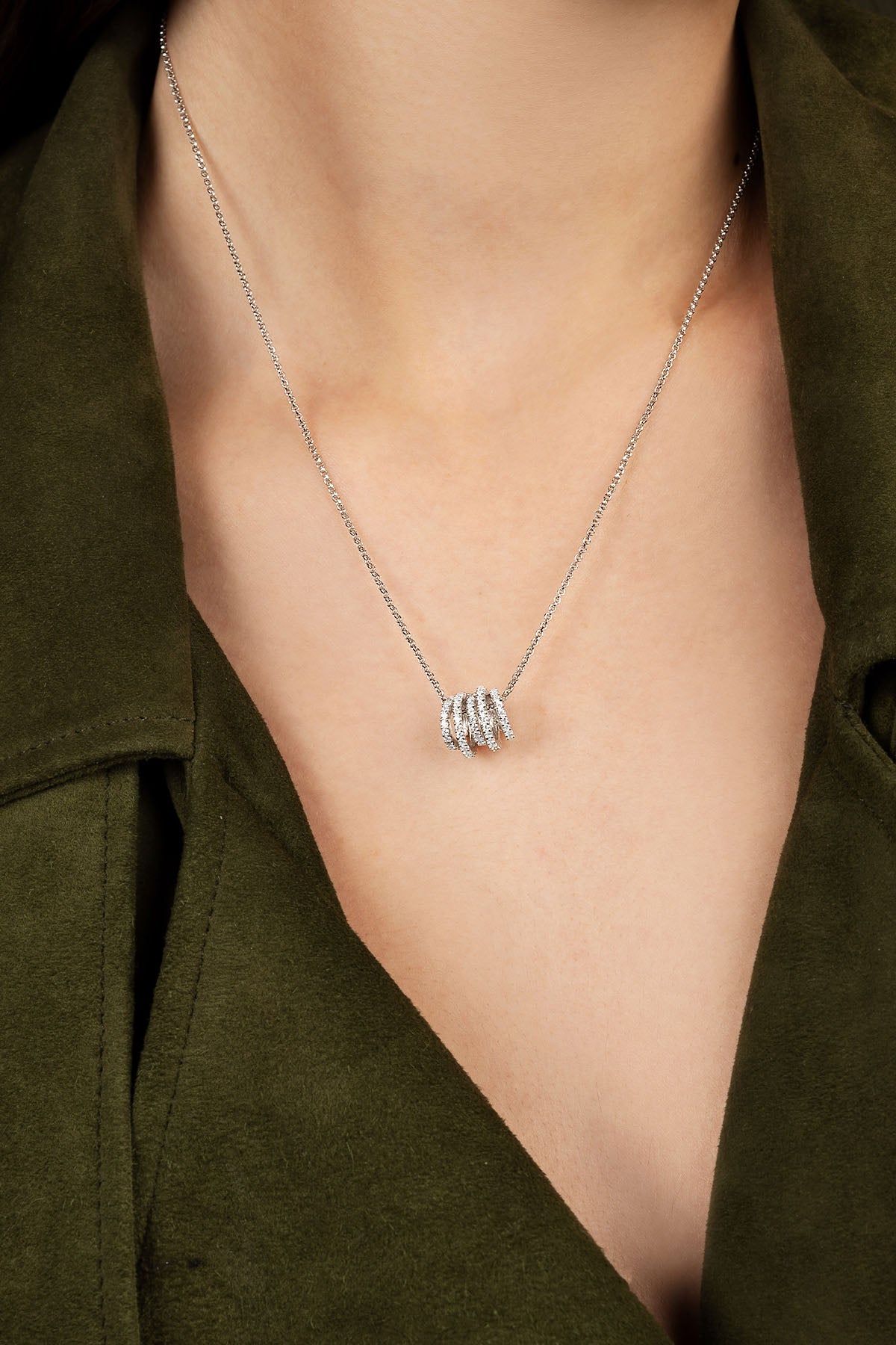 Silver necklace with a pendant on a person wearing a green jacket.