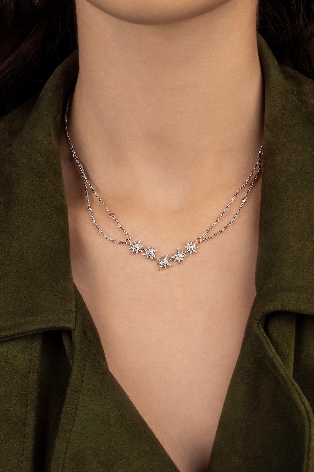 Necklace with star-shaped pendants on a person wearing a green garment.