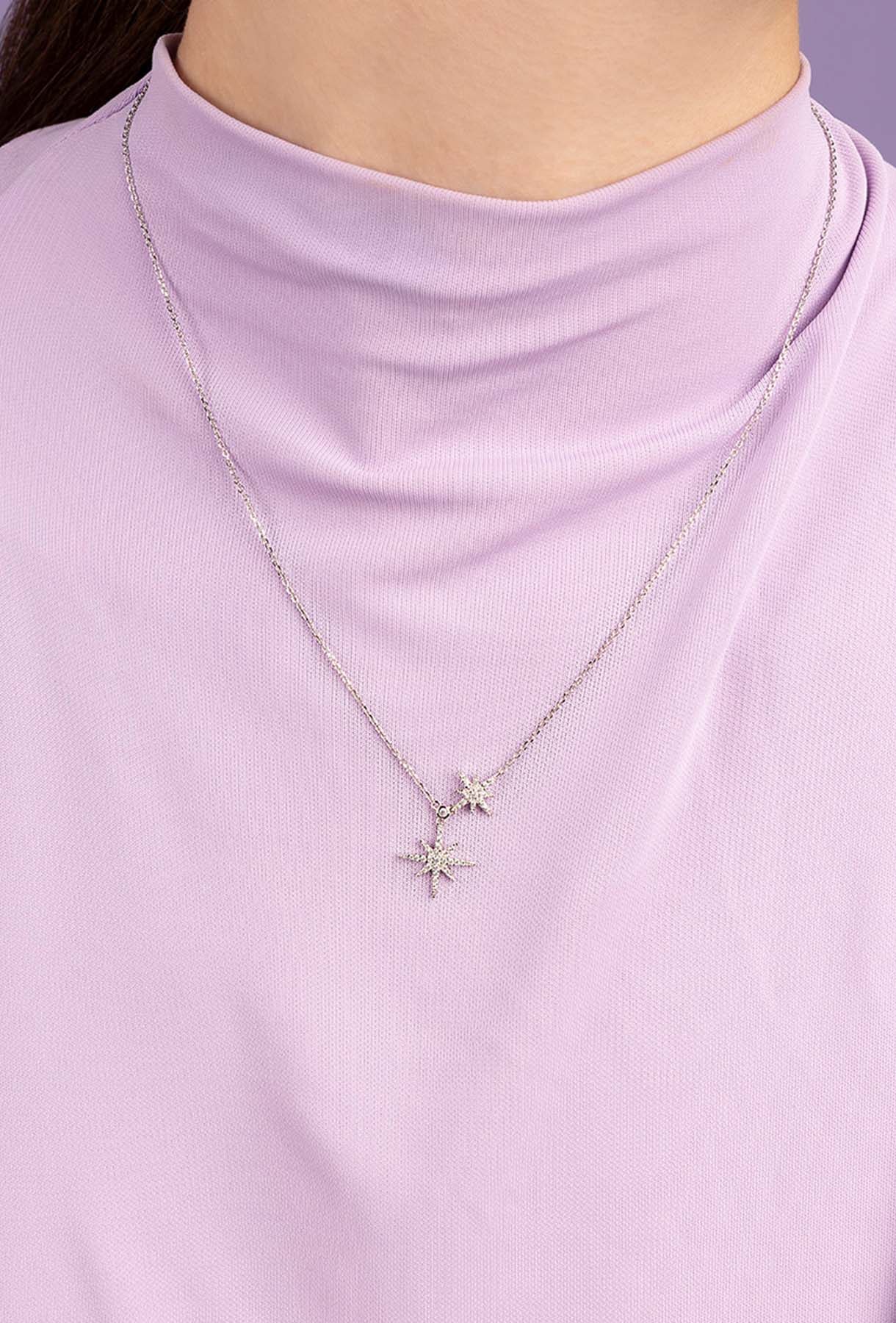 Necklace with star-shaped pendants on a person wearing a light purple top.