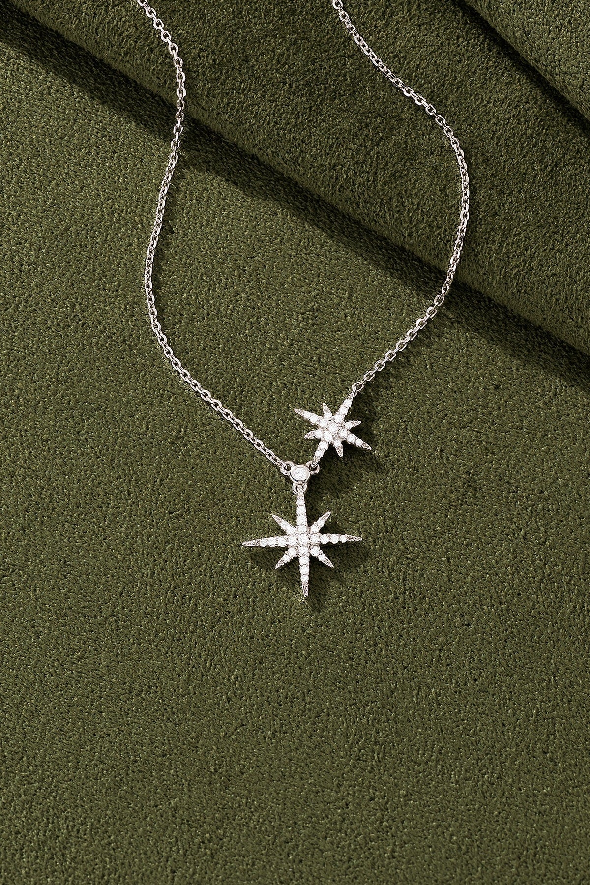 Silver star-shaped necklace on a green textured surface