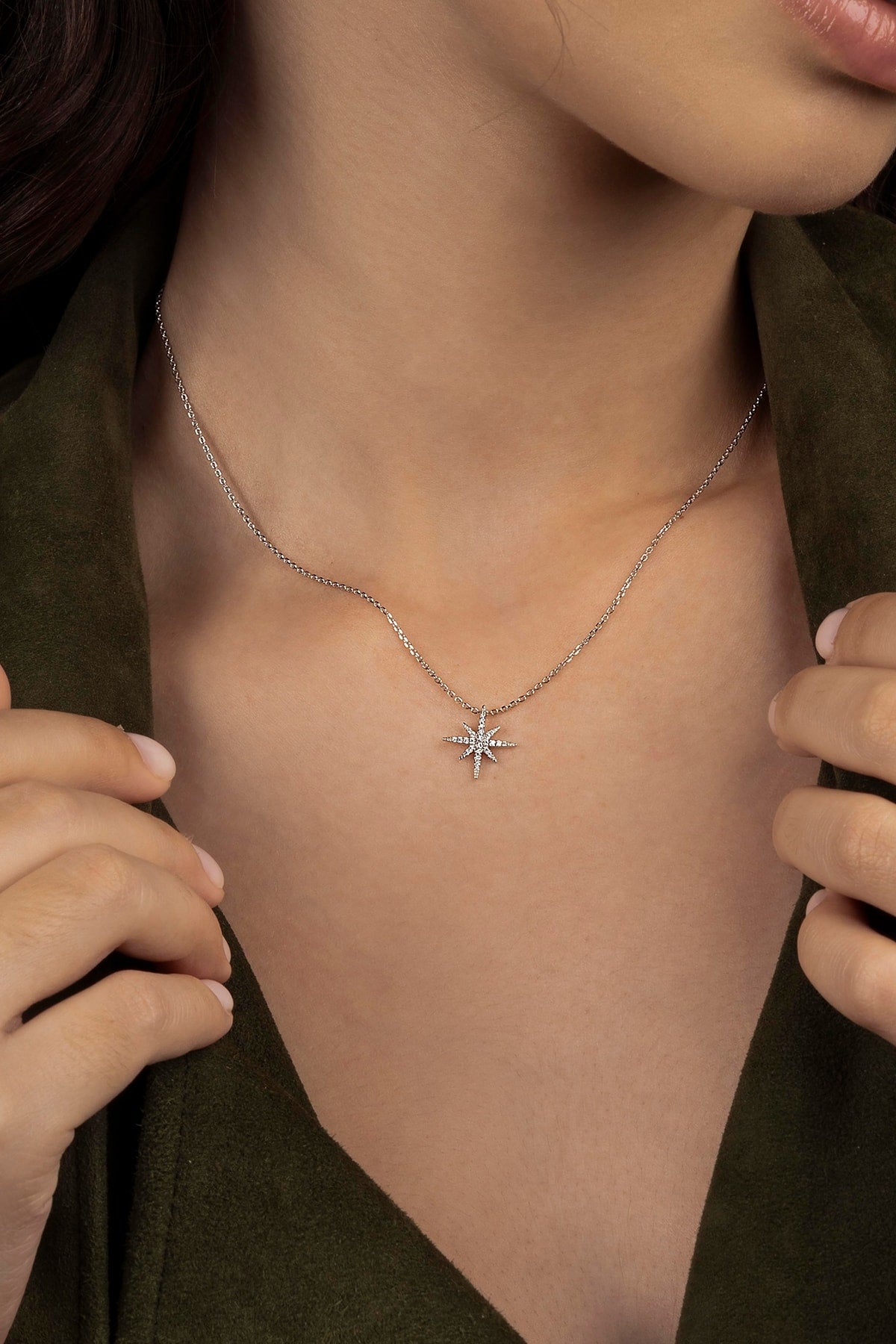 Close-up of a person wearing a silver necklace with a star pendant.