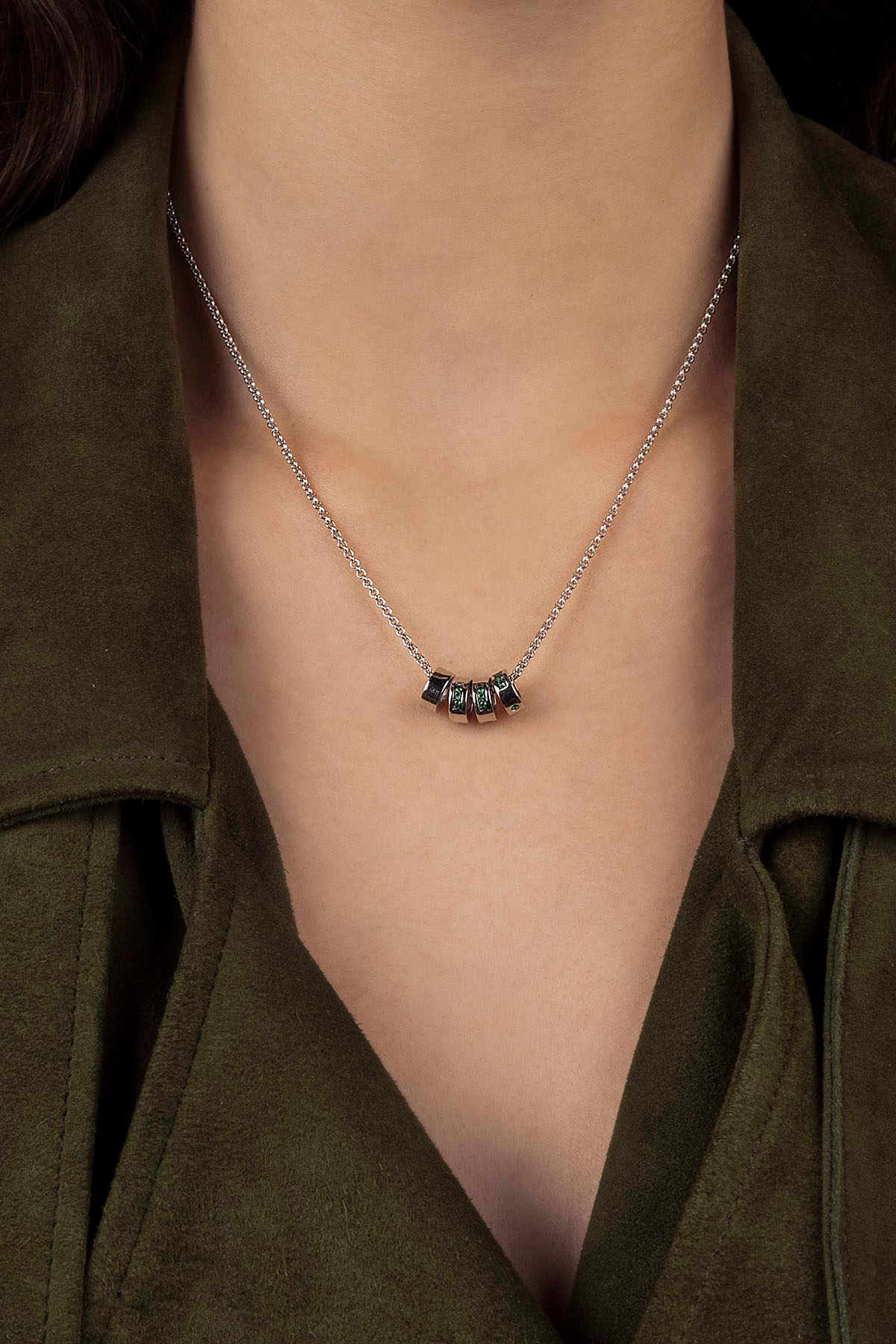 Necklace with a pendant worn by a person in an olive green coat.