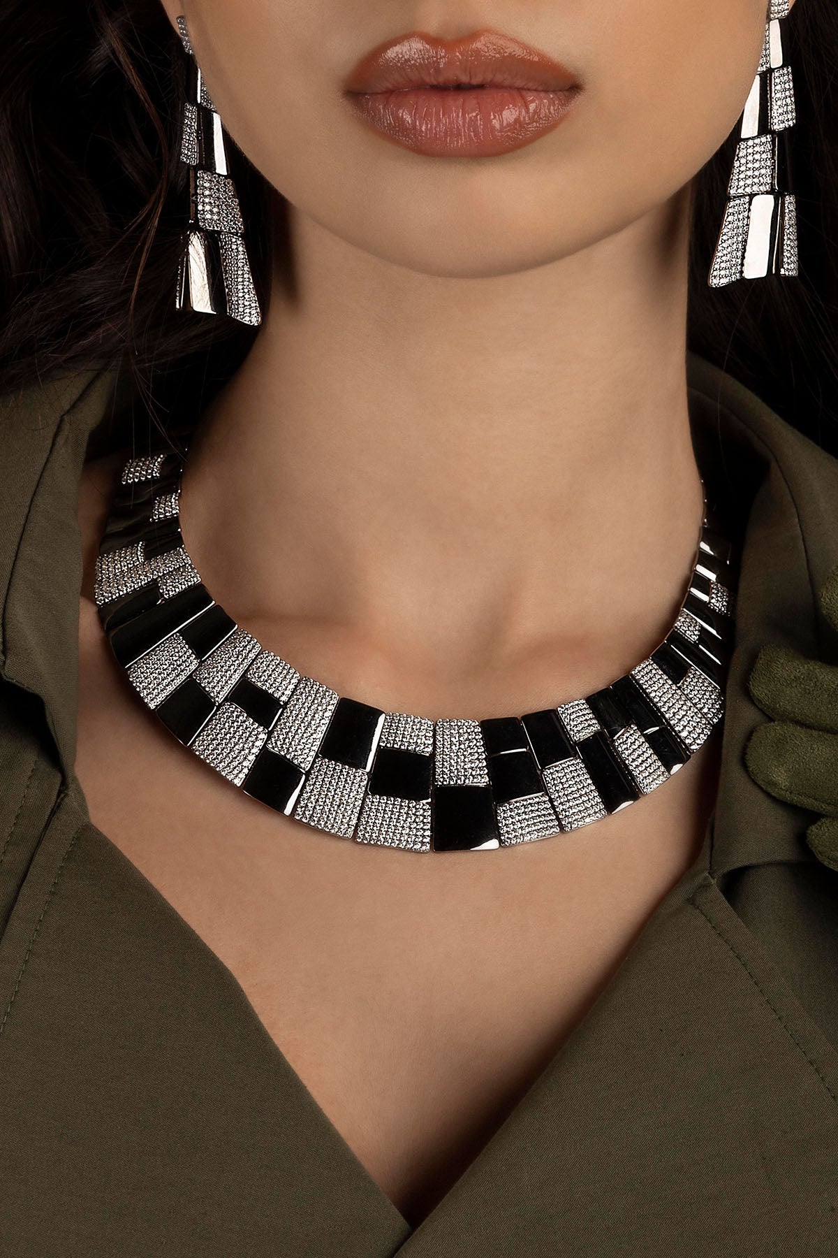 Close-up of a person wearing a geometric necklace with a blurred background