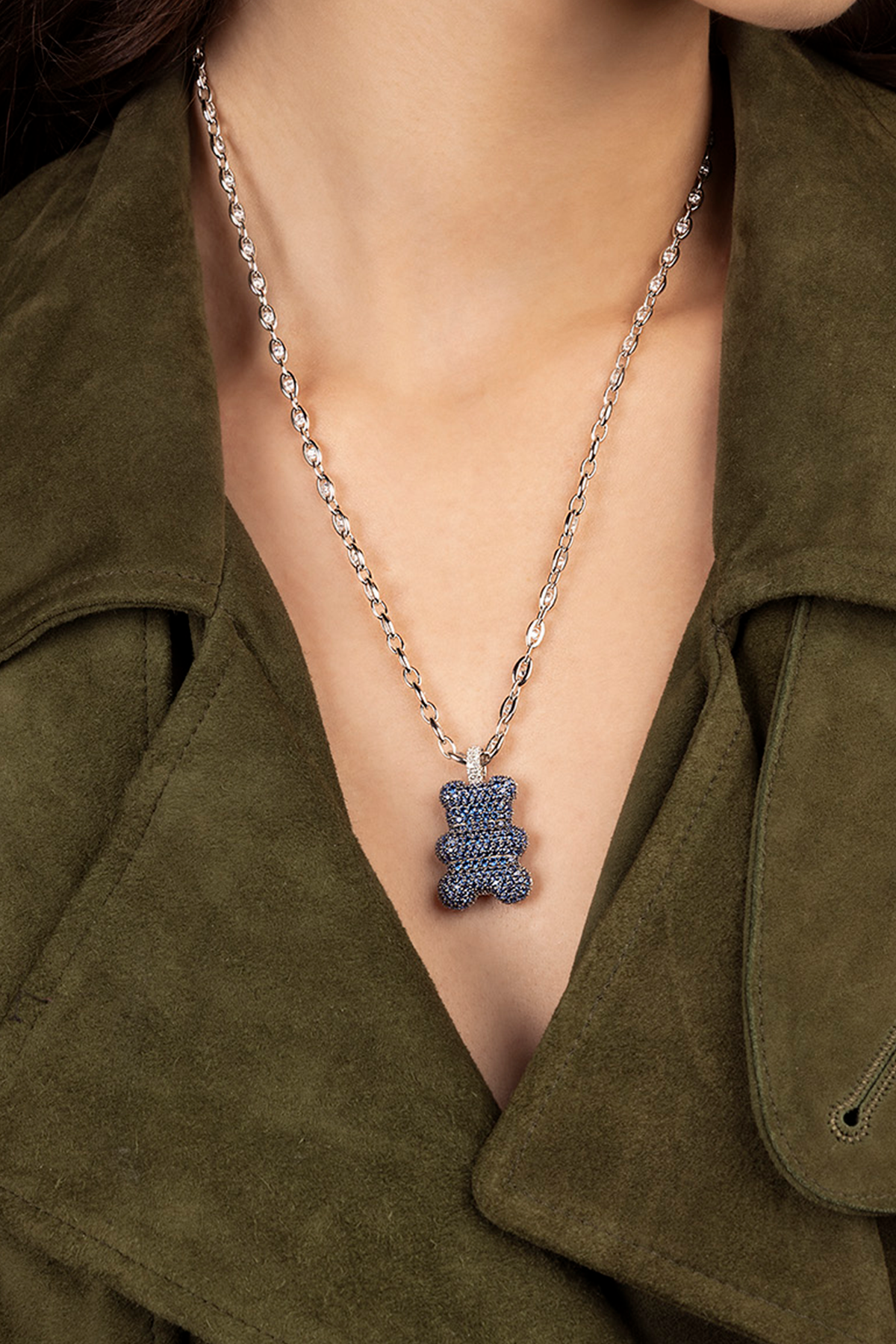 APM MONACO Necklace with a YUMMY bear-shaped pendant worn by a person in an olive green jacket.