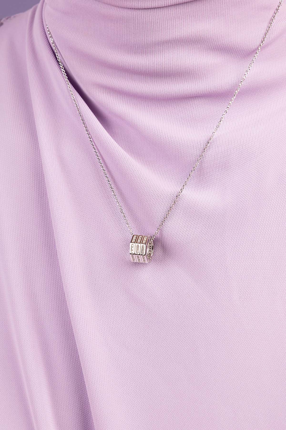 Silver necklace with a pendant on a light purple fabric background
