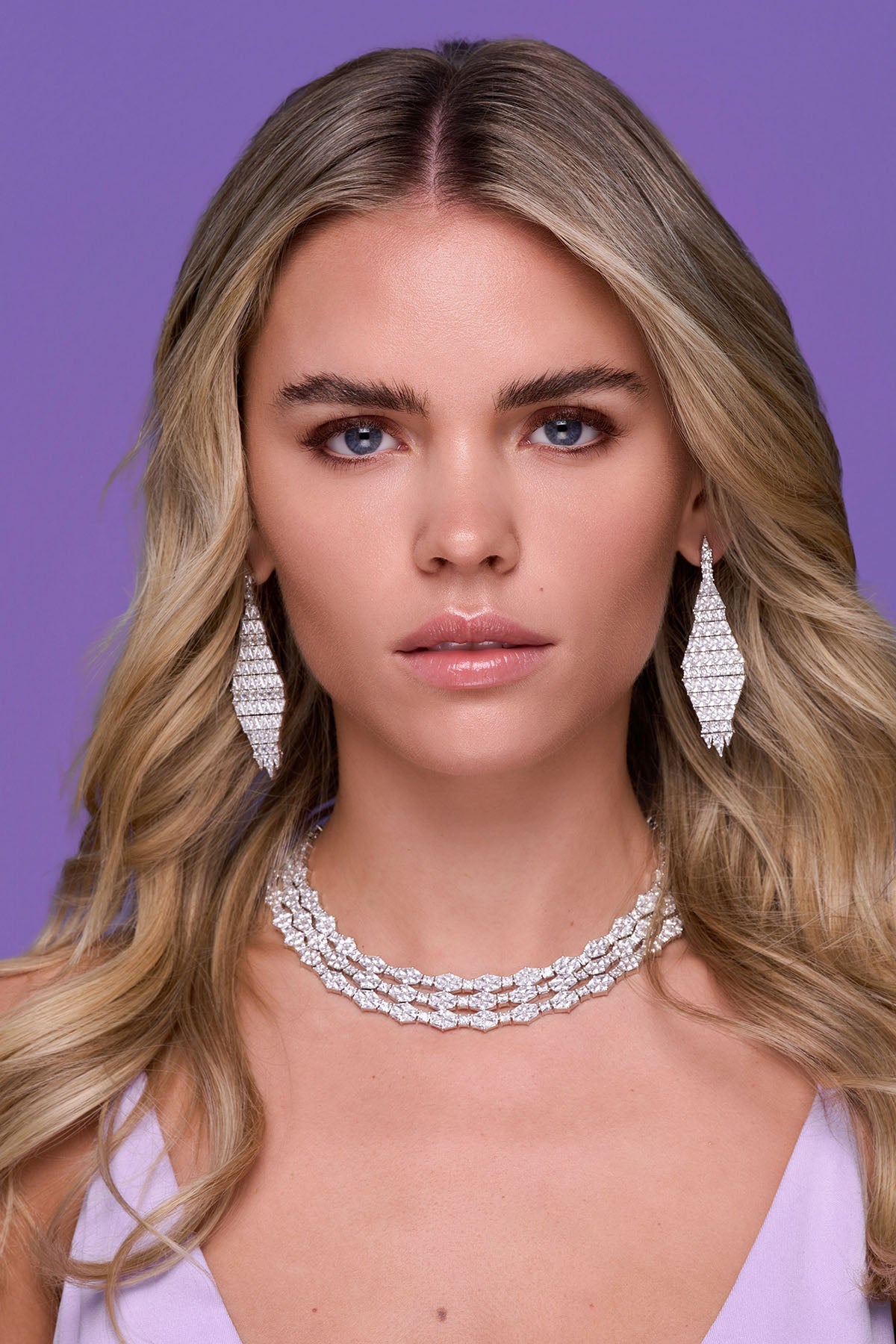 a person wearing the drop earrings on a purple background