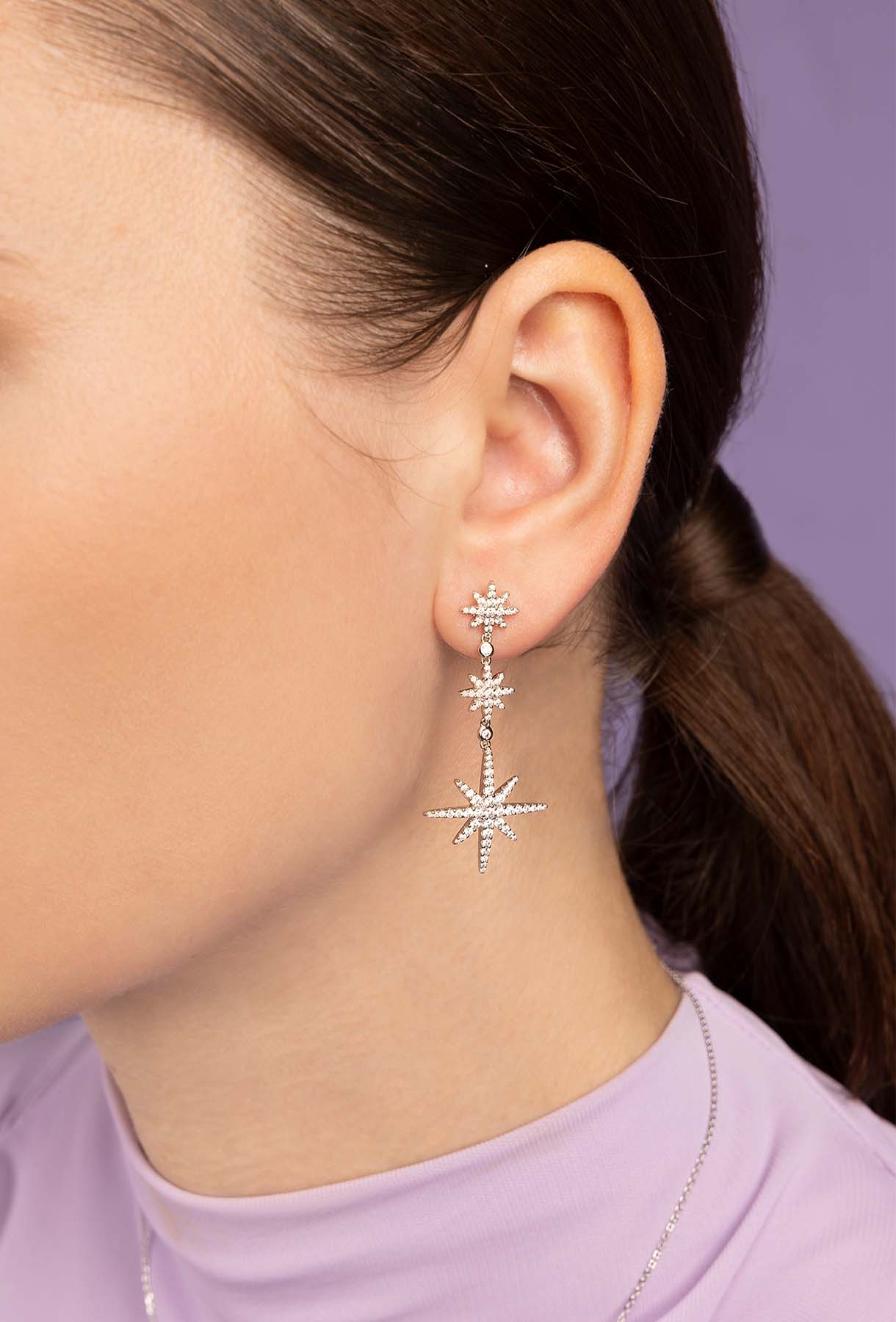 Star-shaped earrings worn by a person with a blurred background