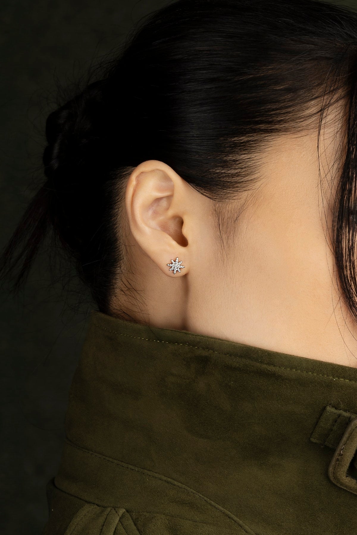 Close-up of an ear wearing a earring with a dark background