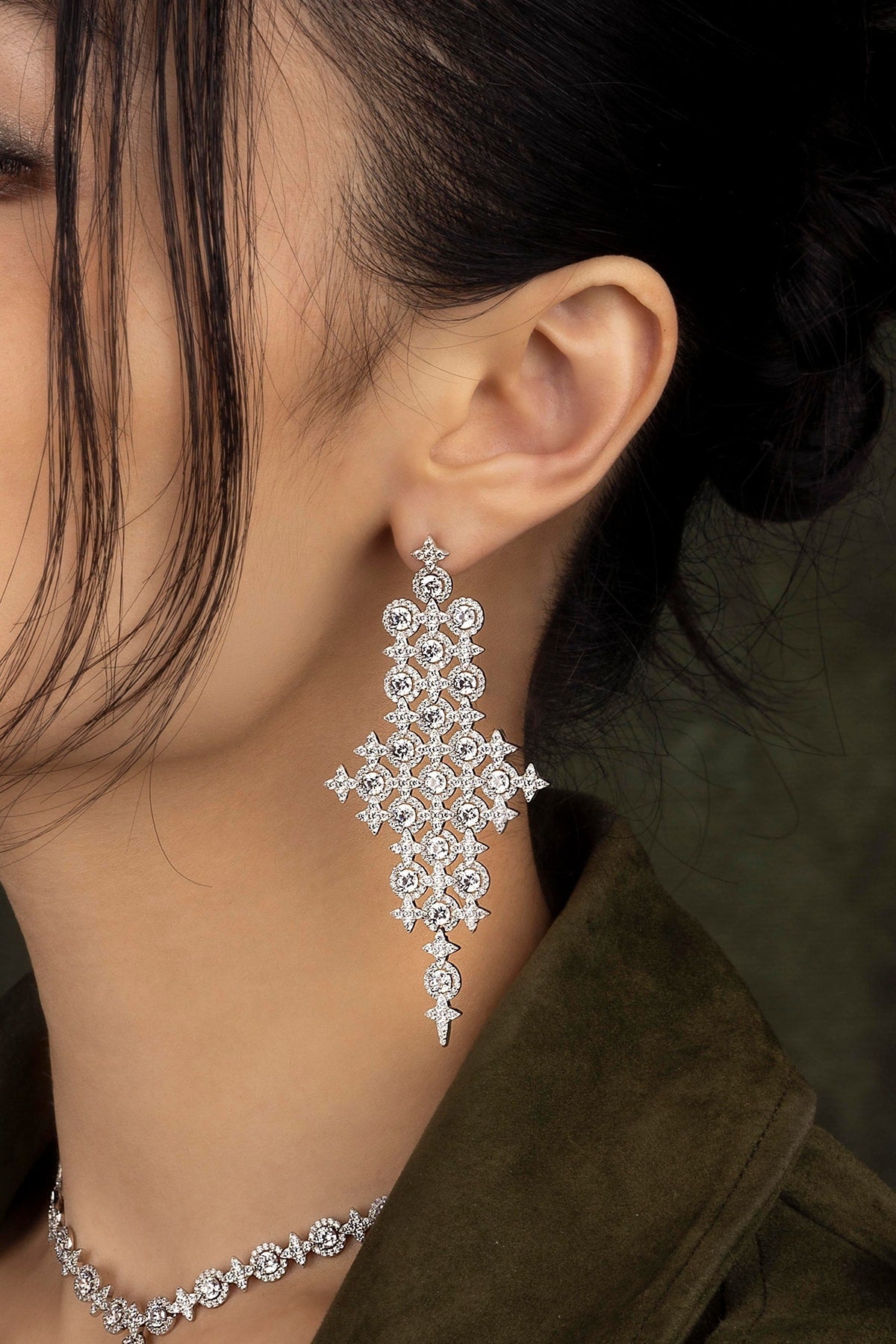 Close-up of a person wearing a sparkling earring with a dark background