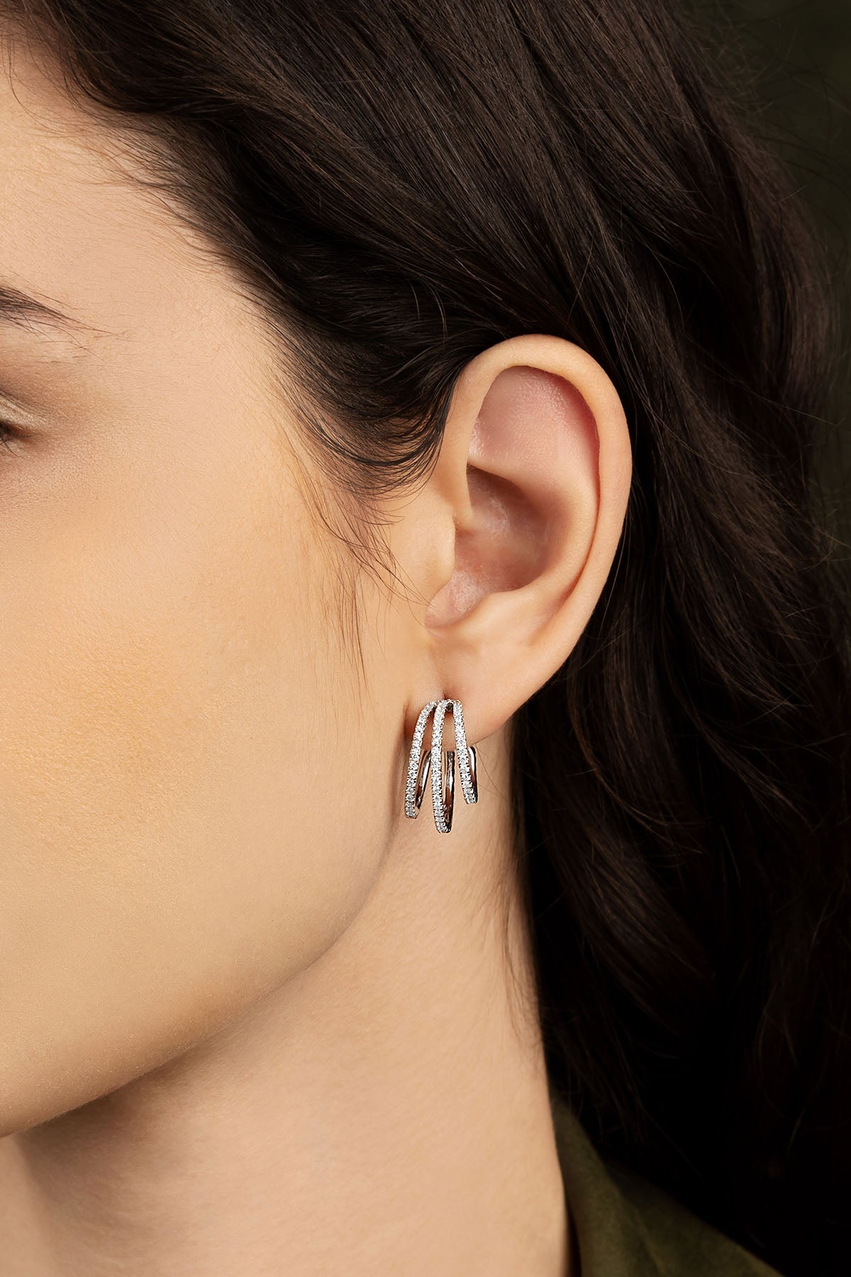 Close-up of a person wearing silver hoop earrings with a blurred background