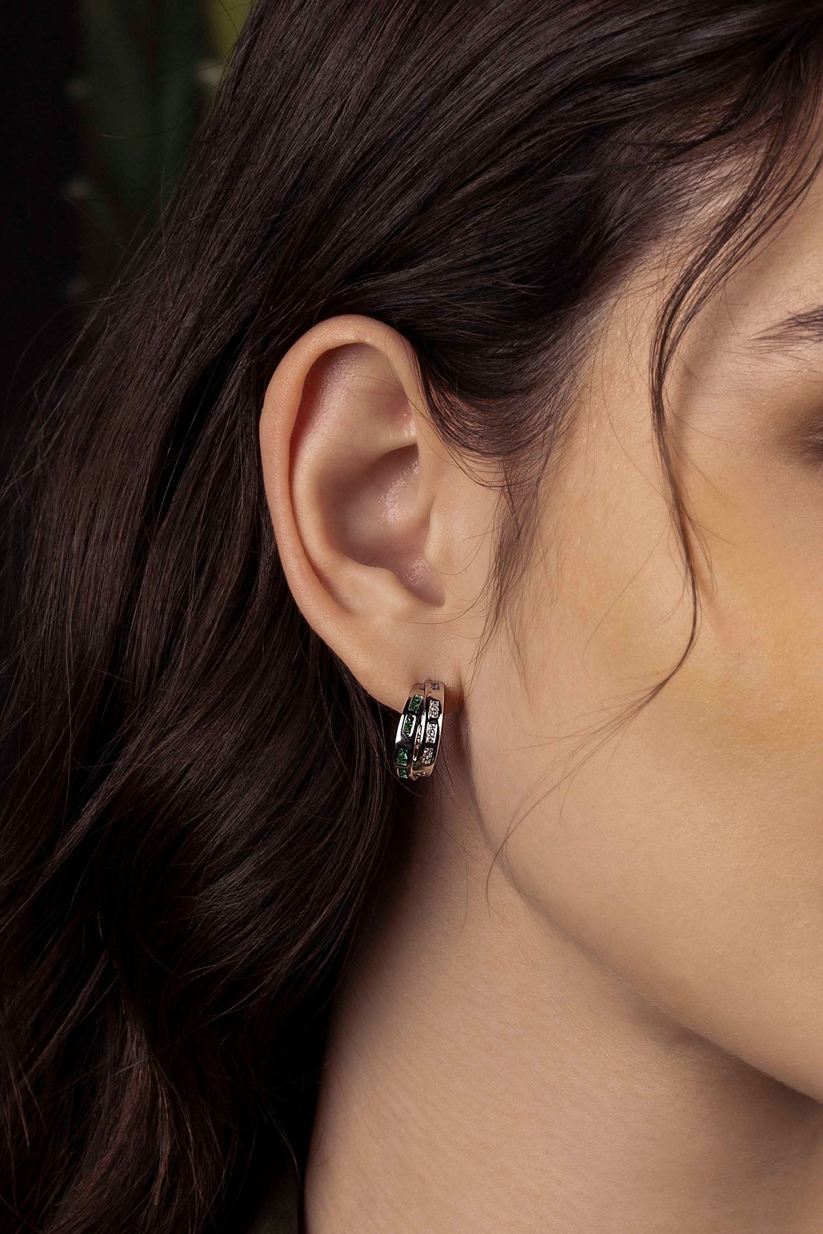 Close-up of an ear wearing a small hoop earring with a blurred background