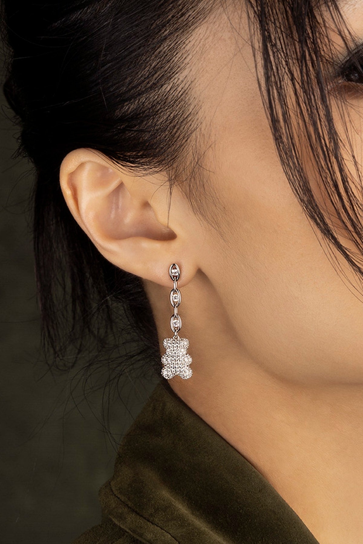 Close-up of a model wearing a silver earring with a dark background