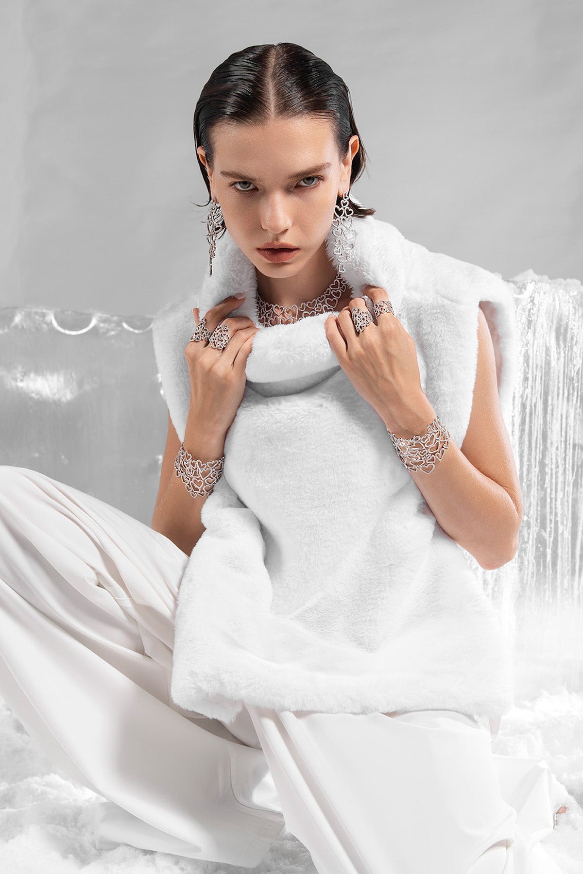 APM MONACO heart-shaped jewelry in silver worn by model with a white fur collar, including bracelets, necklace, earrings and rings