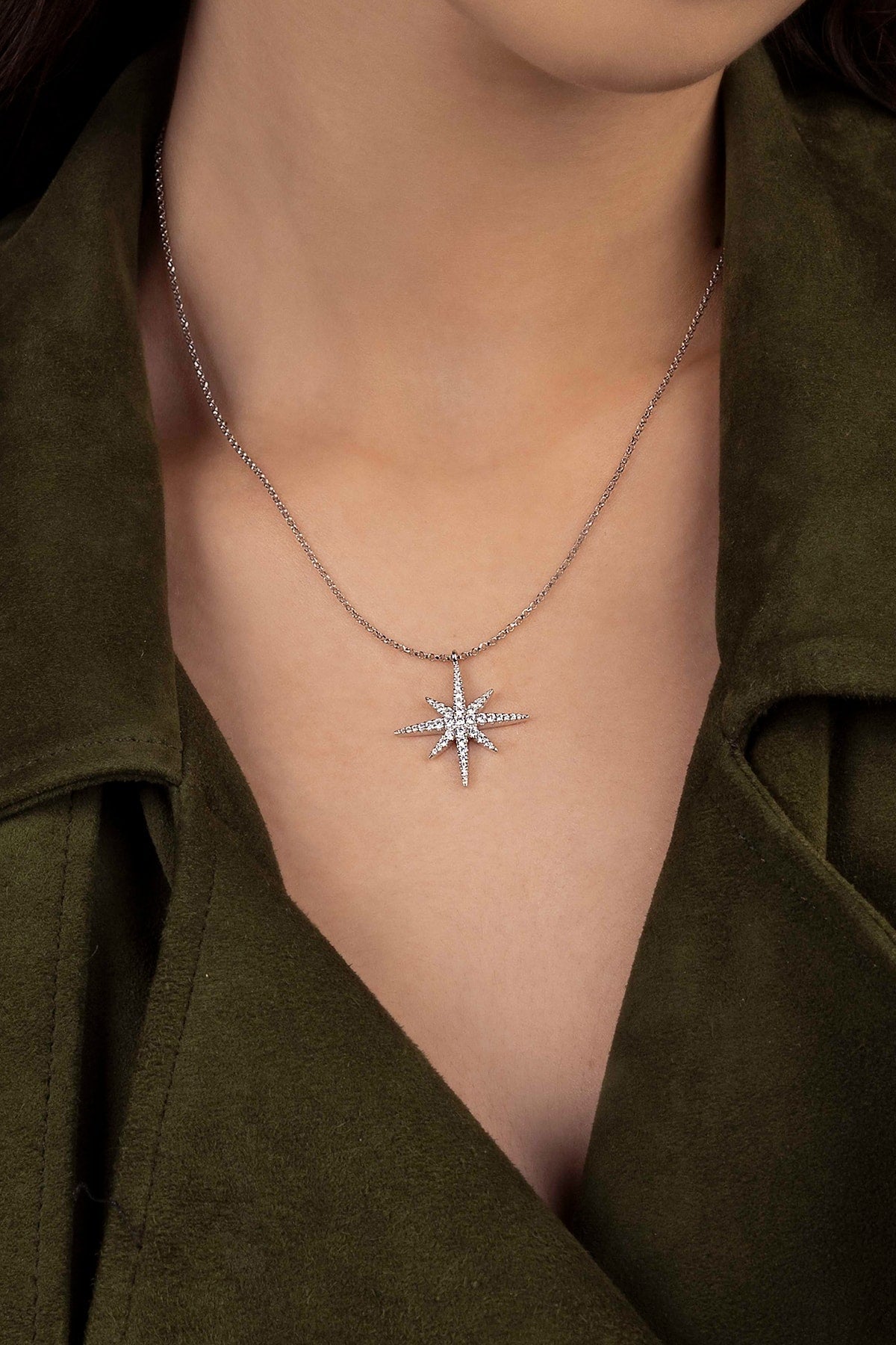 Star-shaped necklace worn by a person with a green garment