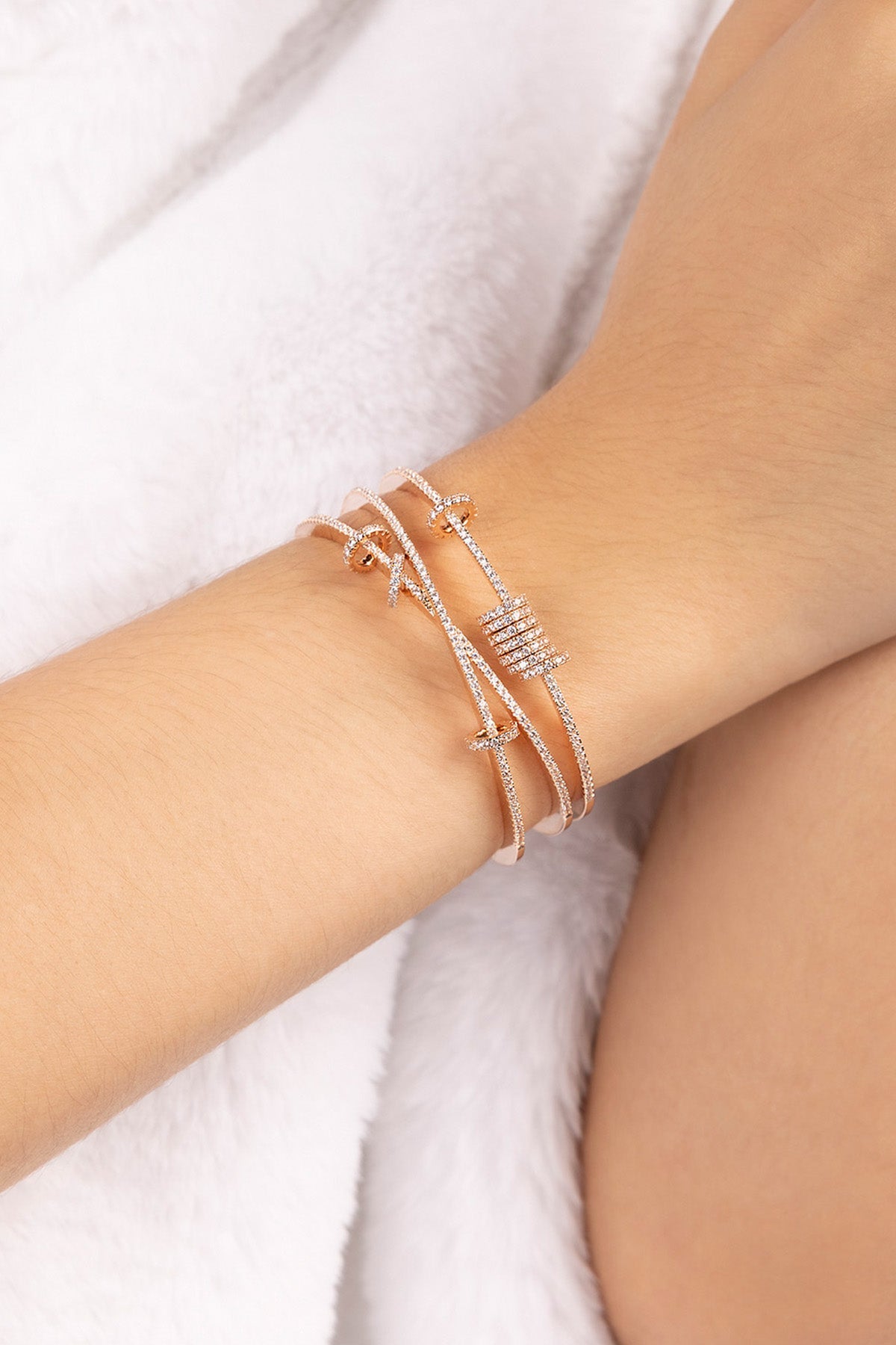 Close-up of a wrist wearing APM MONACO rose gold open cuff with sliding design on a white background