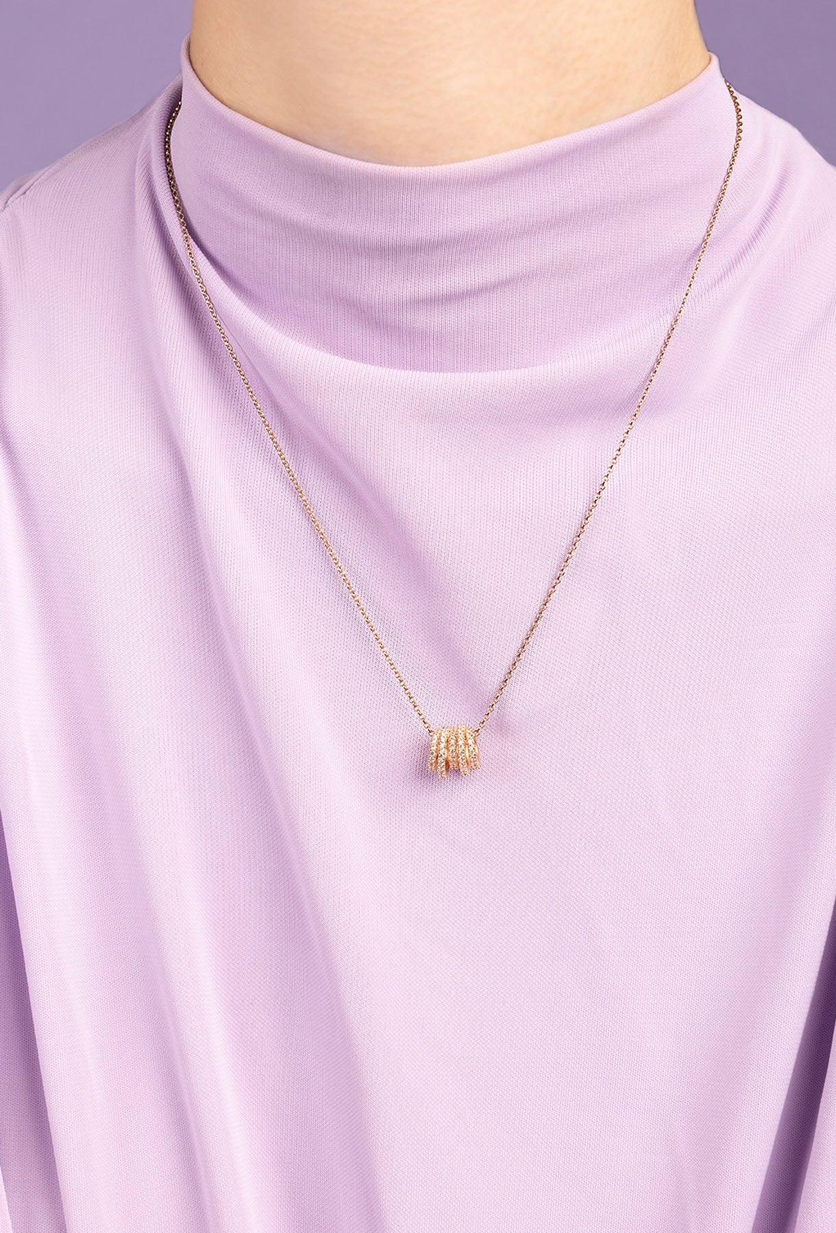 APM MONACO rose gold hoop adjustable necklace on a person wearing a light purple top.