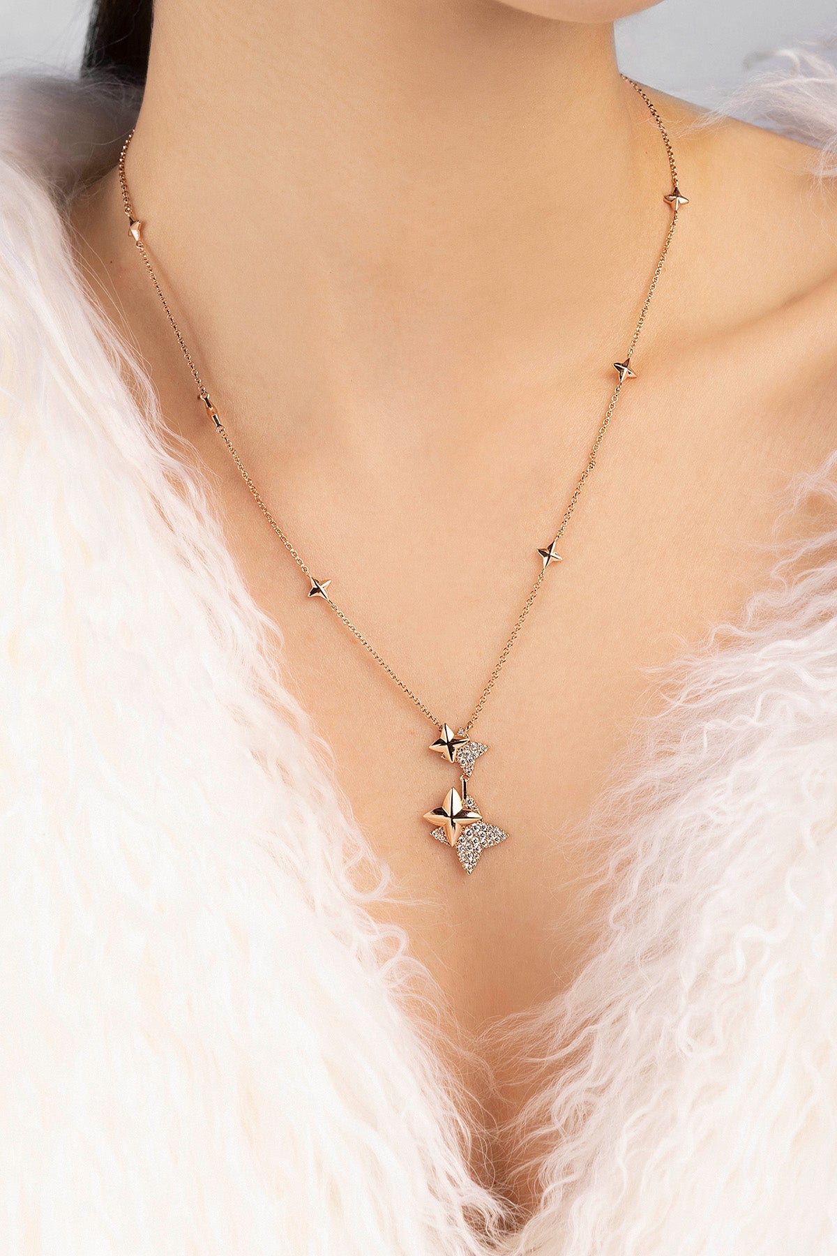 Necklace with star-shaped pendant on a person wearing a white fur garment.