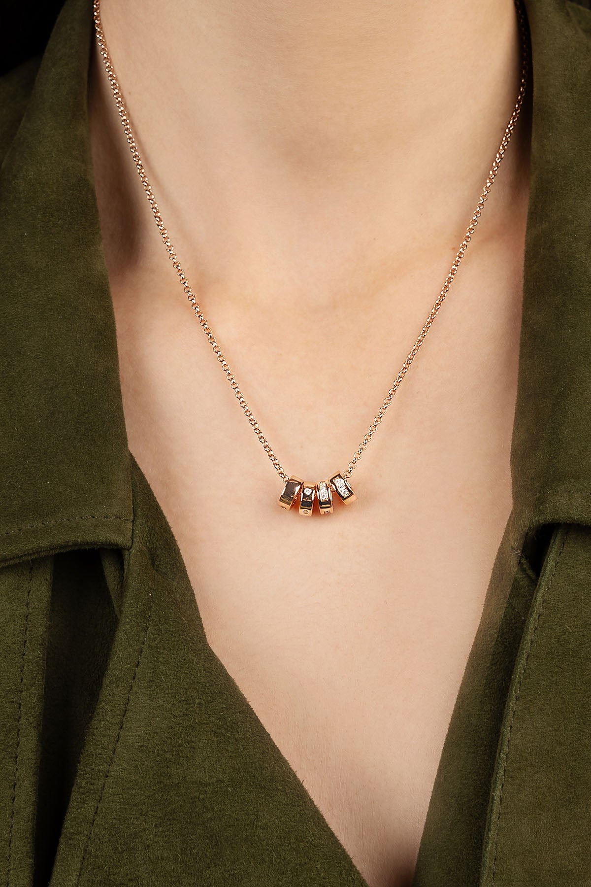 Necklace with small four pendants on a person wearing a green garment.