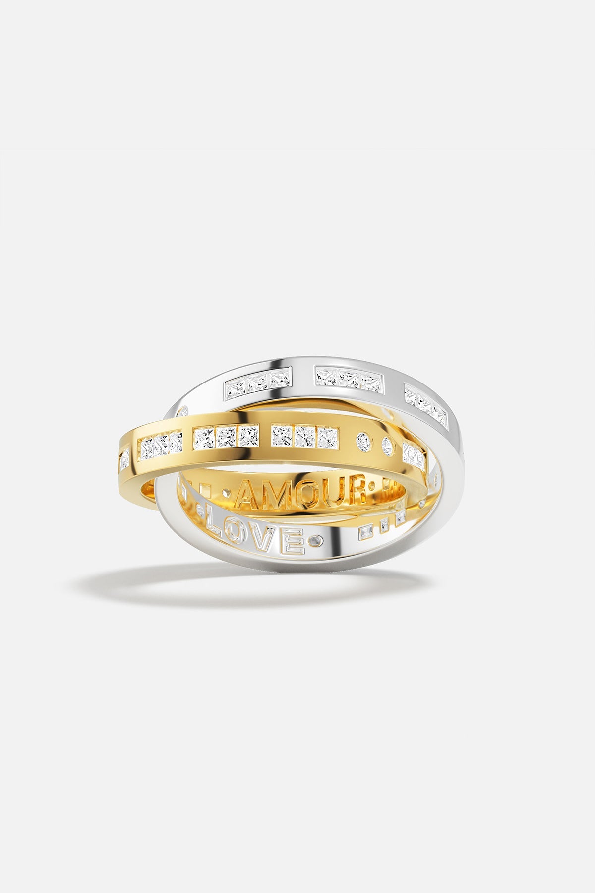 Rings APM Monaco: three interlocking rings—Silver-tone with pavé diamonds, yellow-gold with pavé diamonds, and a Silver-tone ring engraved AMOUR and LOVE.