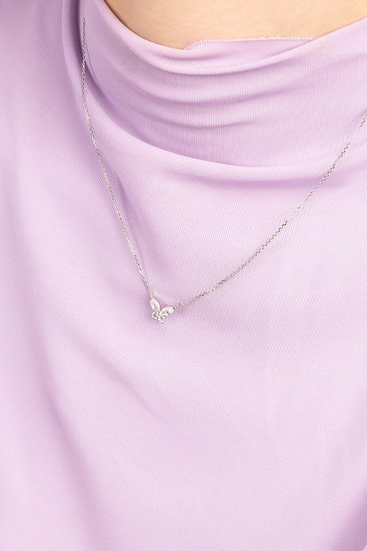 APM MONACO butterfly necklace with a small pendant on a light purple top
