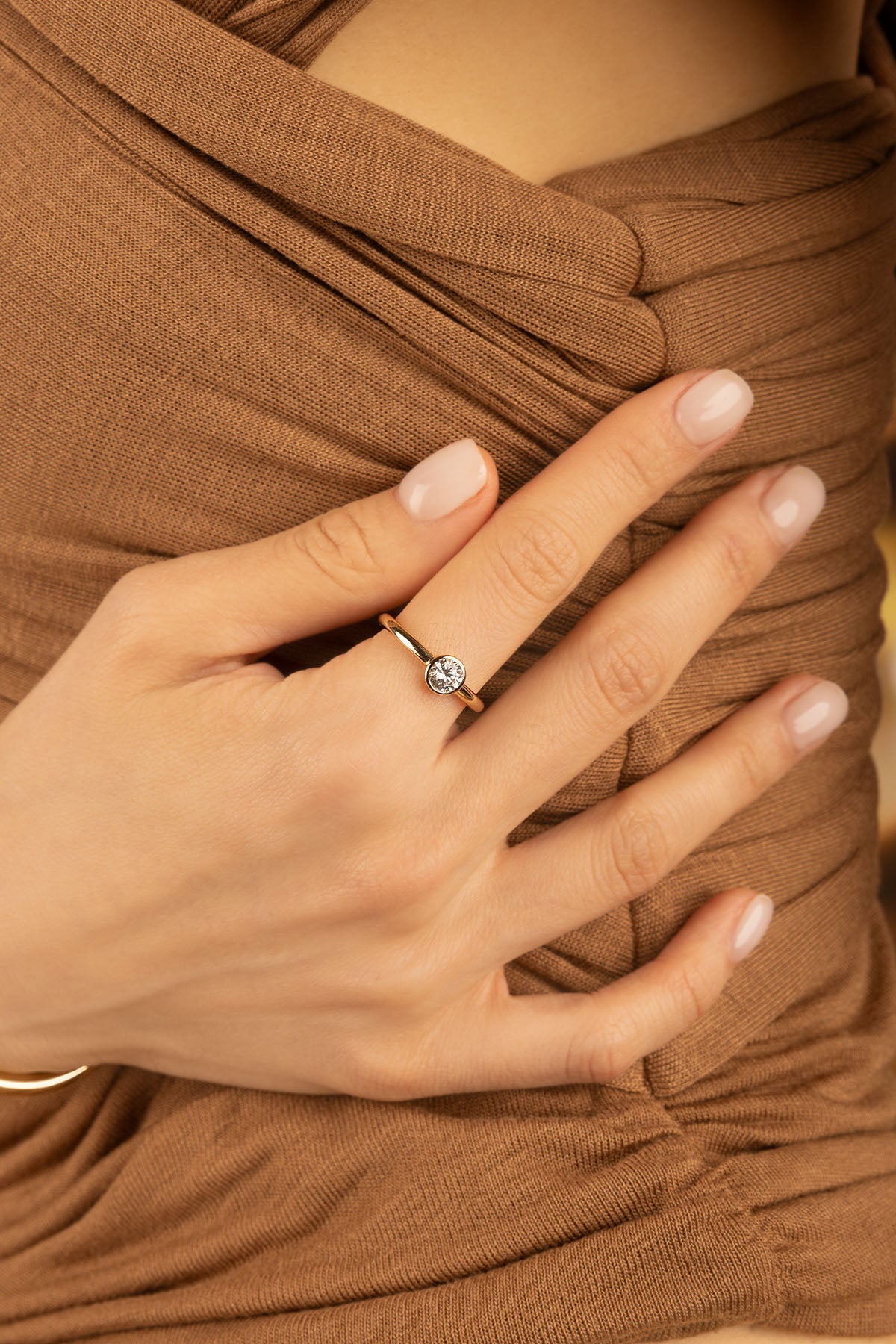 Rings APM Monaco: Yellow gold simple ring with a single round stone on a woman's hand.