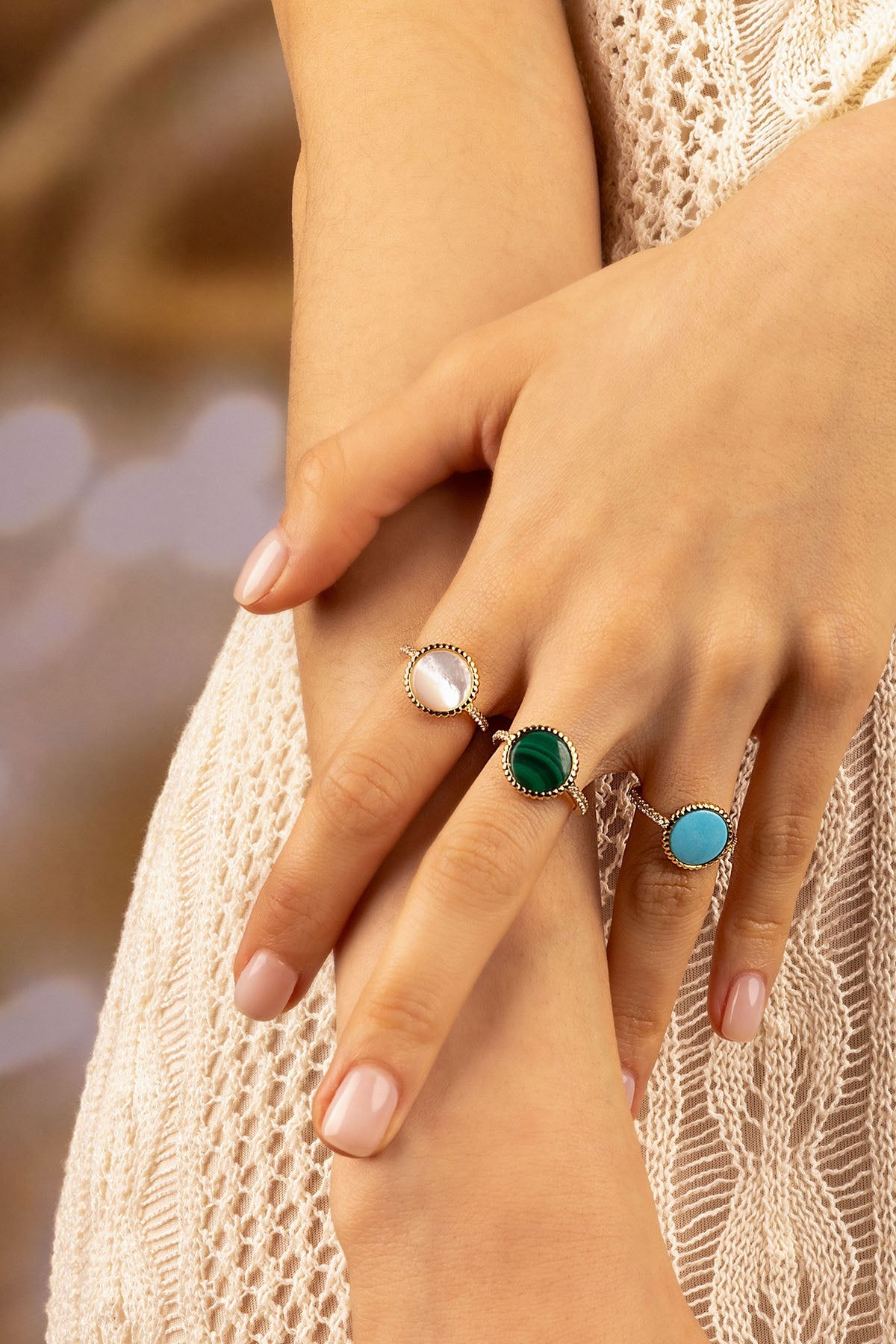 Rings APM Monaco. Three gemstone rings on a woman's hands in white, green, and blue tones, featuring white nacre and meteorite accents.