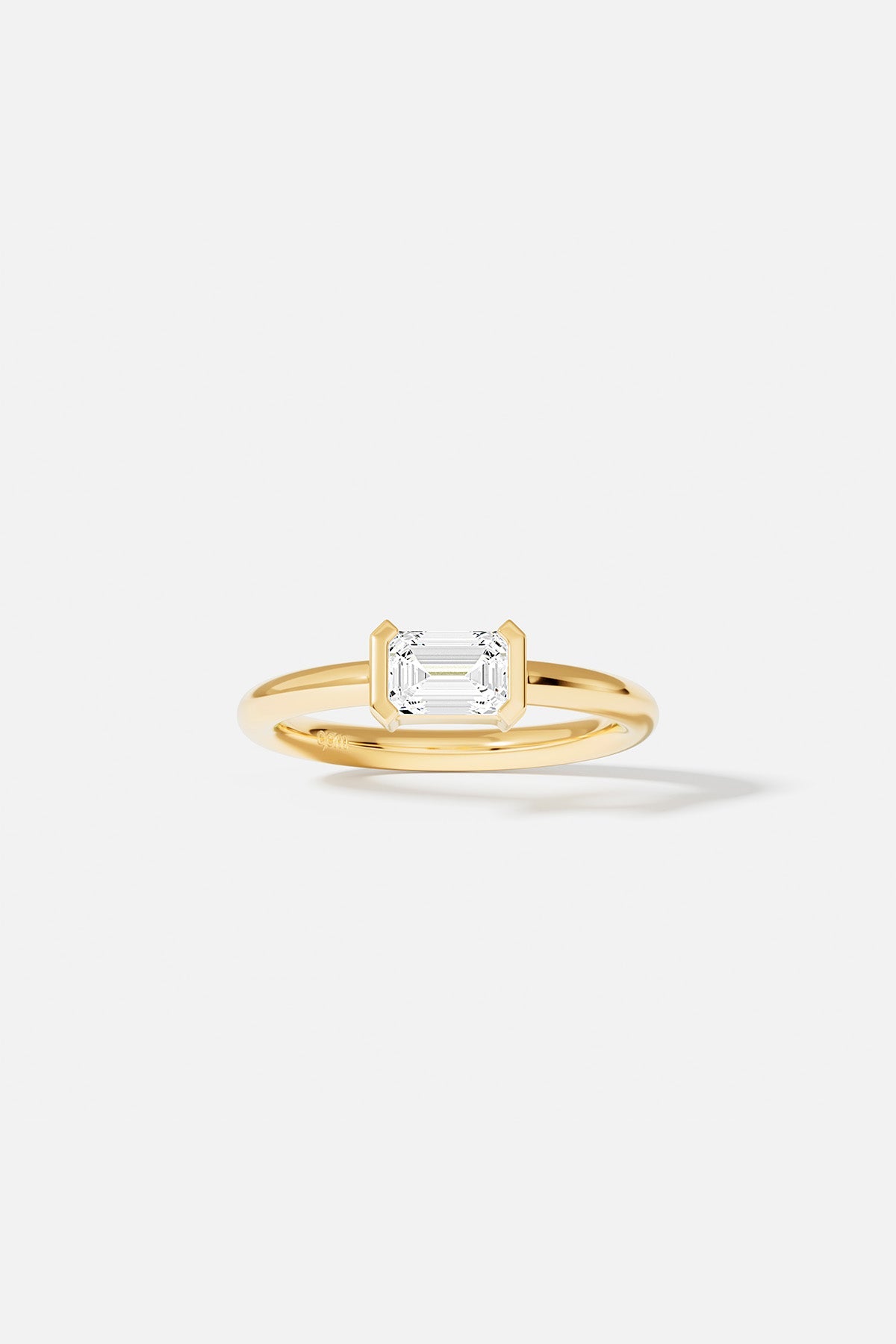 Rings APM Monaco in yellow gold with a horizontal emerald-cut white diamond centerpiece.