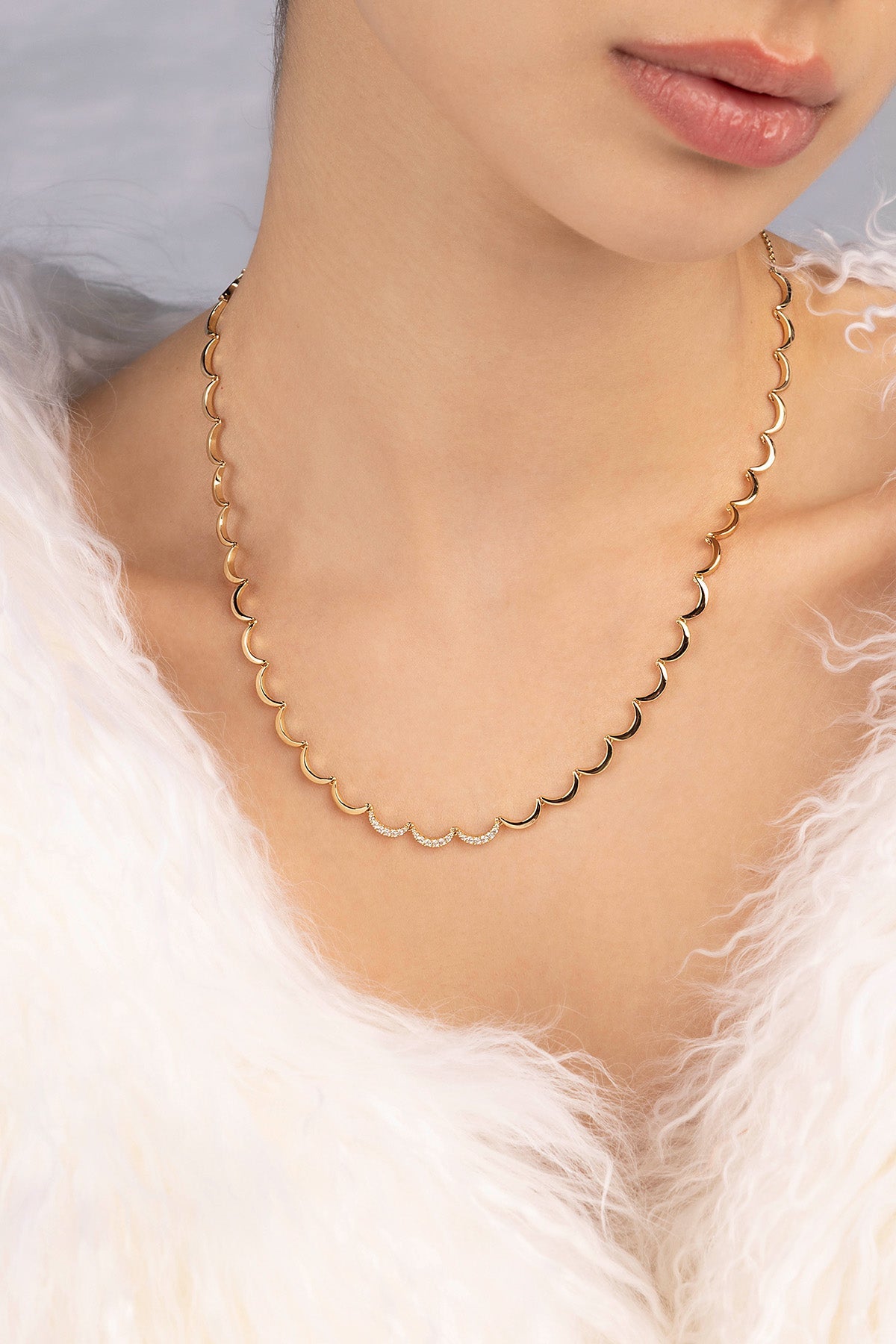 Gold necklace worn by a person with a soft focus background