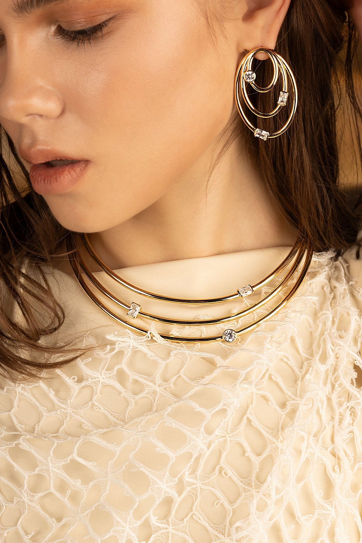 Necklaces APM Monaco: triple gold choker with pavé diamonds; Earrings APM Monaco: oval gold earrings with embedded diamonds.