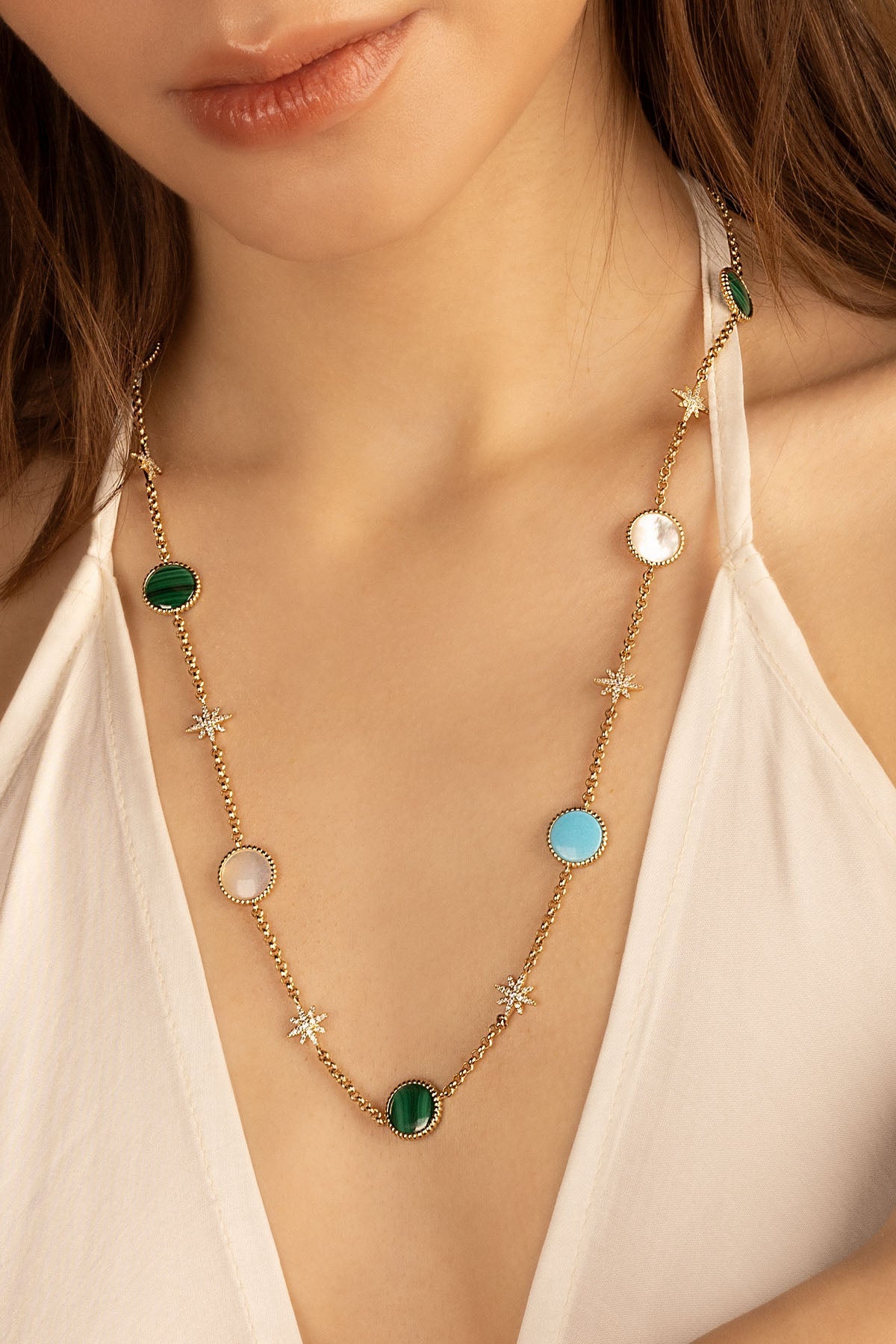 Necklaces APM Monaco fashion jewelry: adjustable chain with small star charms and gemstone accents worn by a woman.